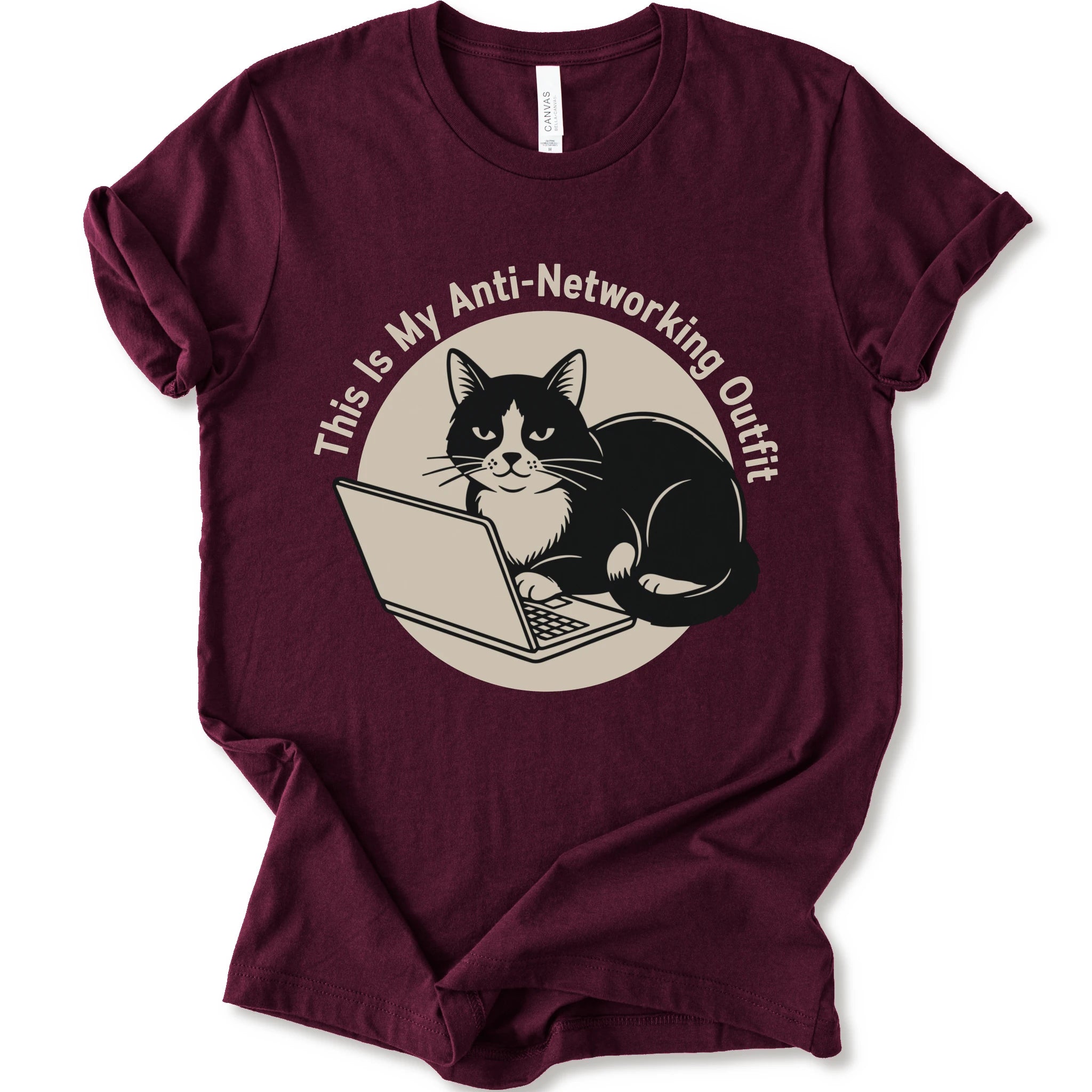 A maroon T-shirt with a “This Is My Anti-Networking Outfit” curves above a black-and-white cat sitting at an open laptop. The artwork uses a clean circular badge layout with a limited black-and-cream palette.