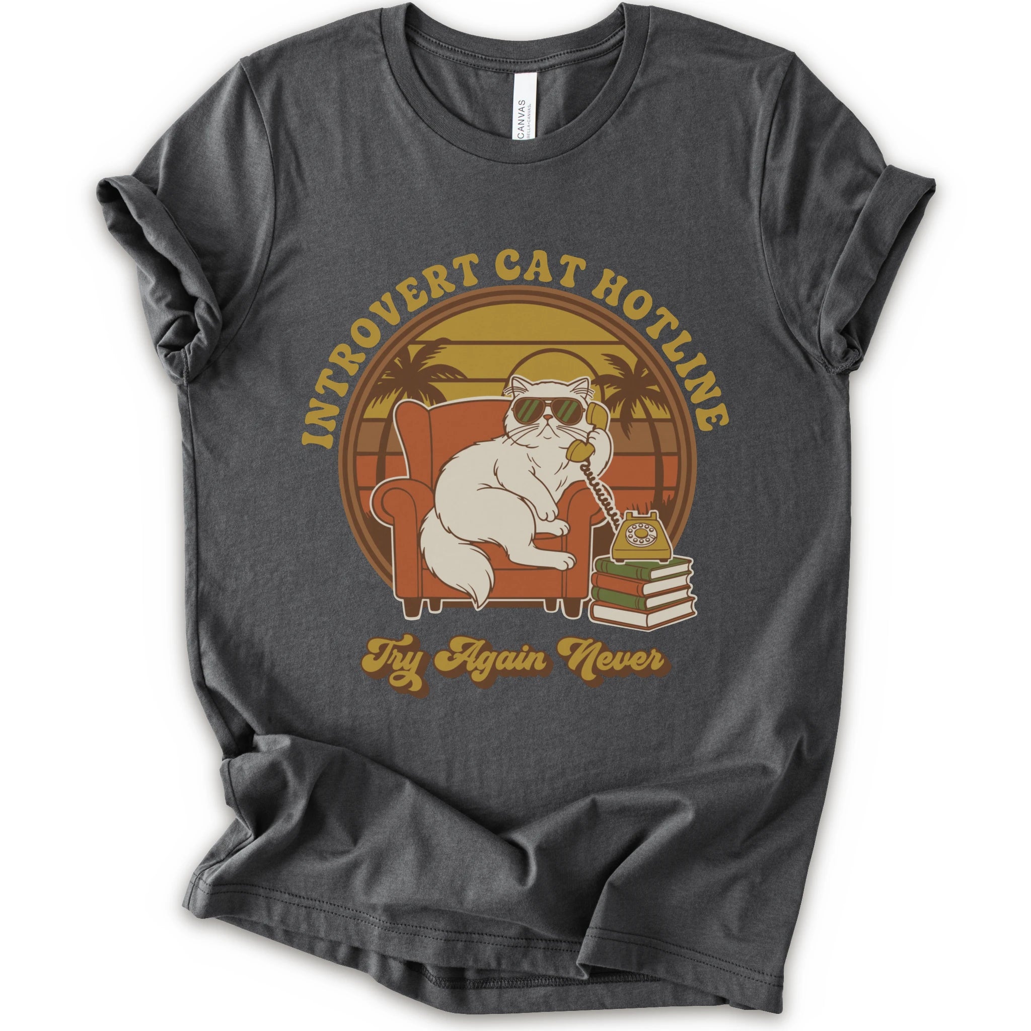 A asphalt short-sleeve crewneck t-shirt with a retro-style graphic of a white cat wearing sunglasses and sitting in an orange armchair, surrounded by the text 'INTROVERT CAT HOTLINE' and 'Try Again Never'.