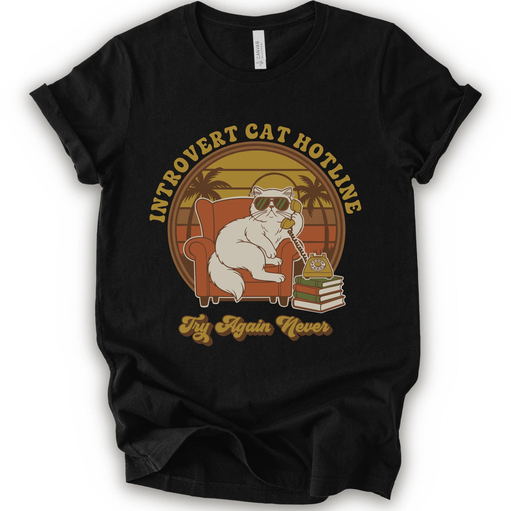 A black short-sleeve crewneck t-shirt with a retro-style graphic of a white cat wearing sunglasses and sitting in an orange armchair, surrounded by the text 'INTROVERT CAT HOTLINE' and 'Try Again Never'.