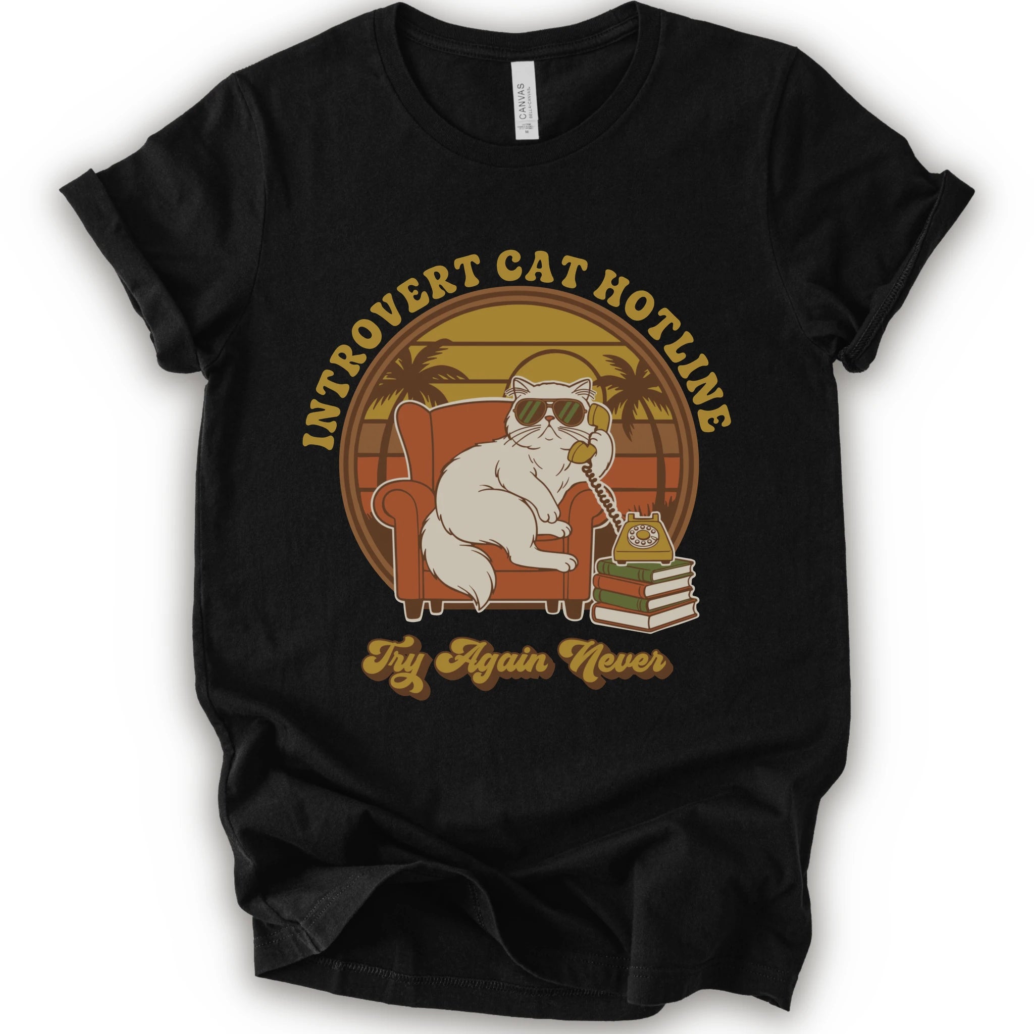 A black short-sleeve crewneck t-shirt with a retro-style graphic of a white cat wearing sunglasses and sitting in an orange armchair, surrounded by the text 'INTROVERT CAT HOTLINE' and 'Try Again Never'.