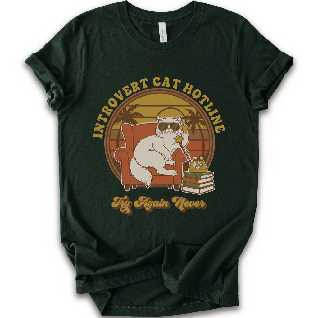 A forest short-sleeve crewneck t-shirt with a retro-style graphic of a white cat wearing sunglasses and sitting in an orange armchair, surrounded by the text 'INTROVERT CAT HOTLINE' and 'Try Again Never'.