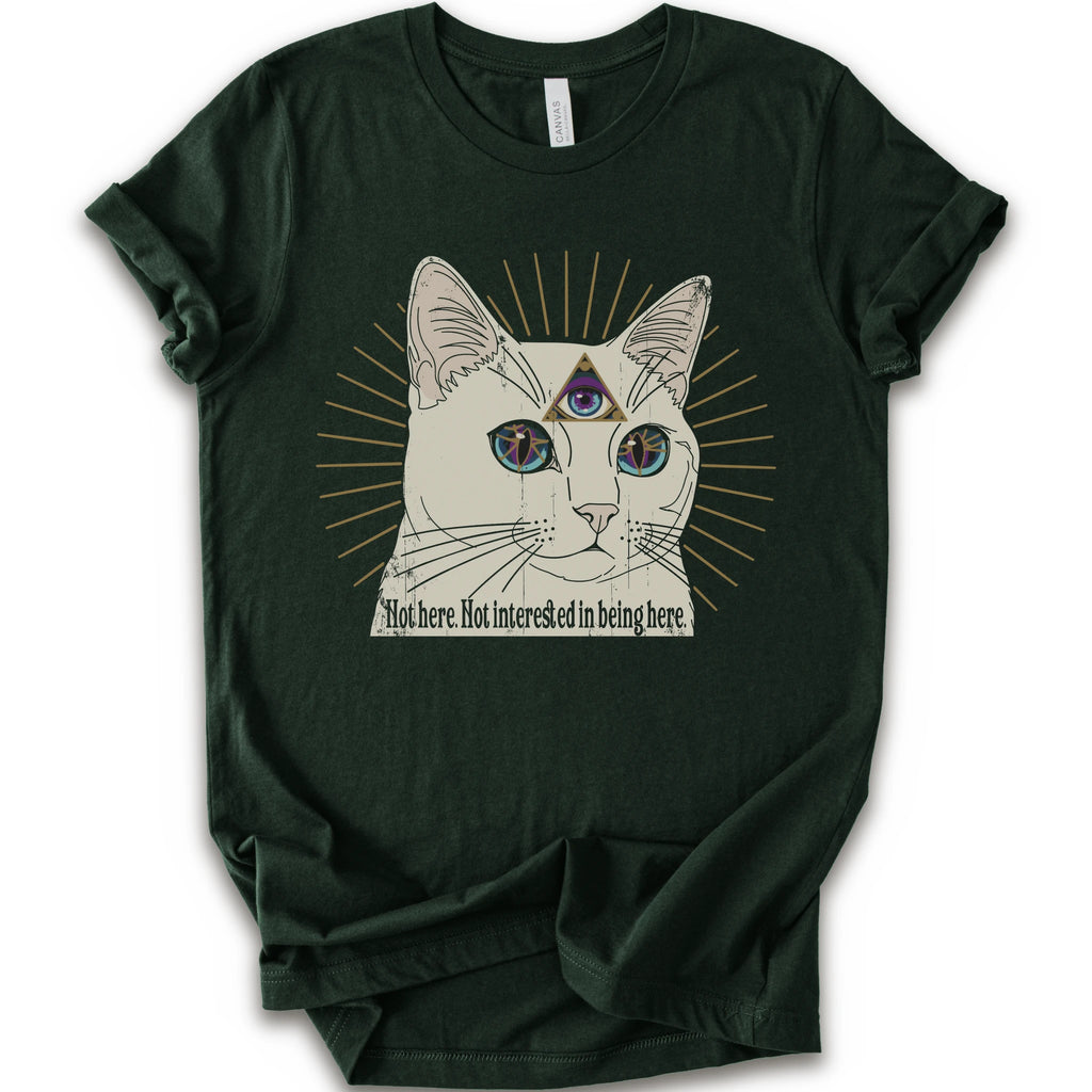 A forest short-sleeve crewneck t-shirt featuring a graphic of a white cat with a third eye and gold sunburst rays, with the text 'Not here. Not interested in being here.