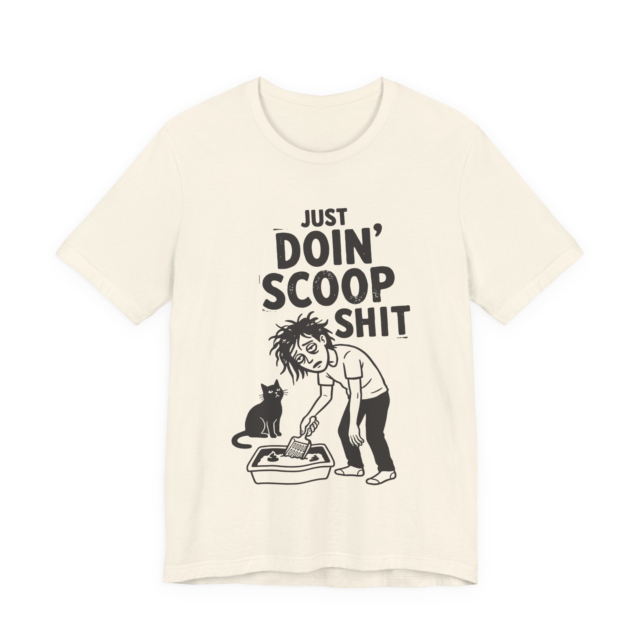 A natural short-sleeve crewneck t-shirt featuring a graphic with 
“Just Doin’ Scoop Shit” text above a tired cat owner cleaning a litter box beside a seated cat