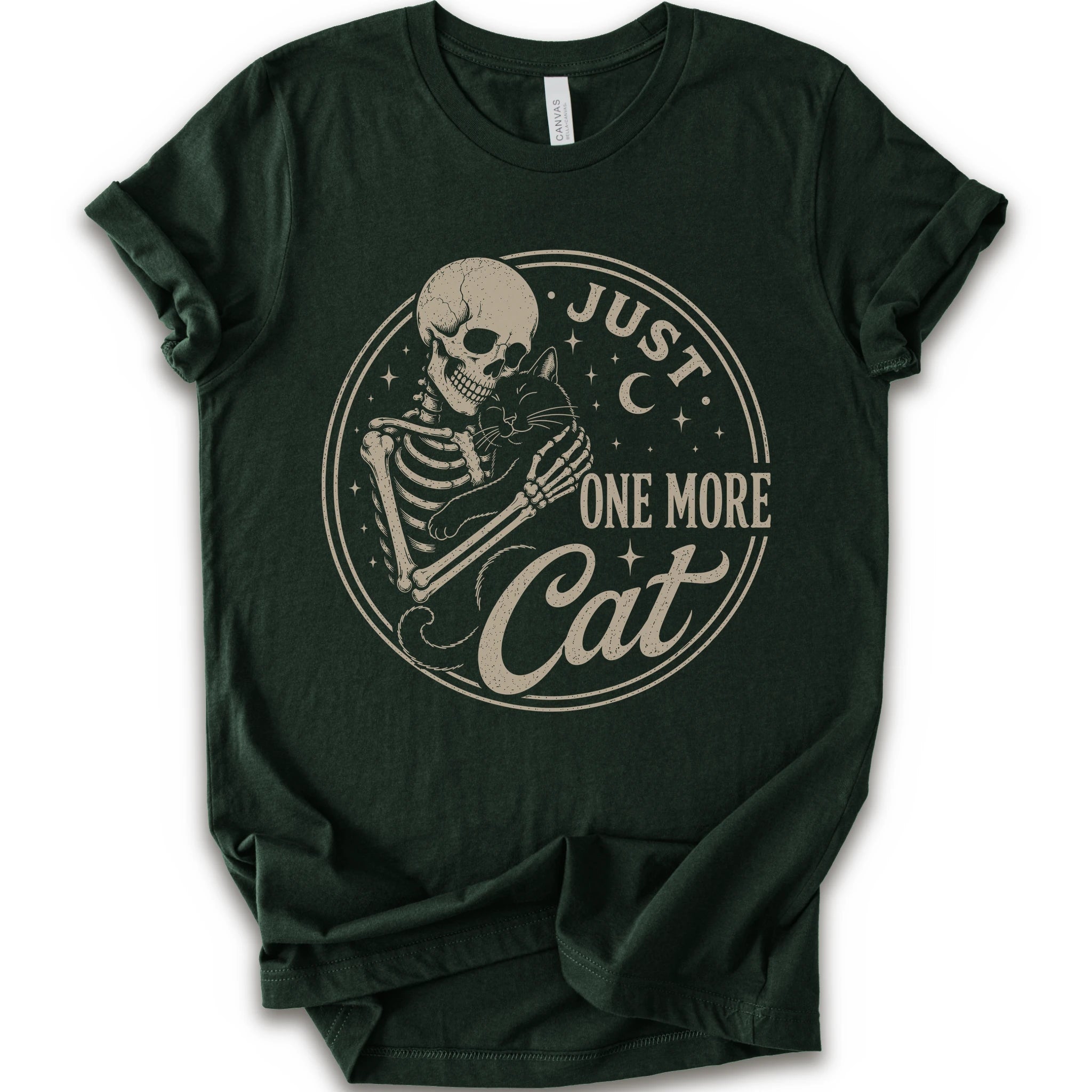 A dark forest green short-sleeve t-shirt with a vintage-style beige graphic on the front showing a skeleton holding a cat, with the text 'JUST ONE MORE Cat'.