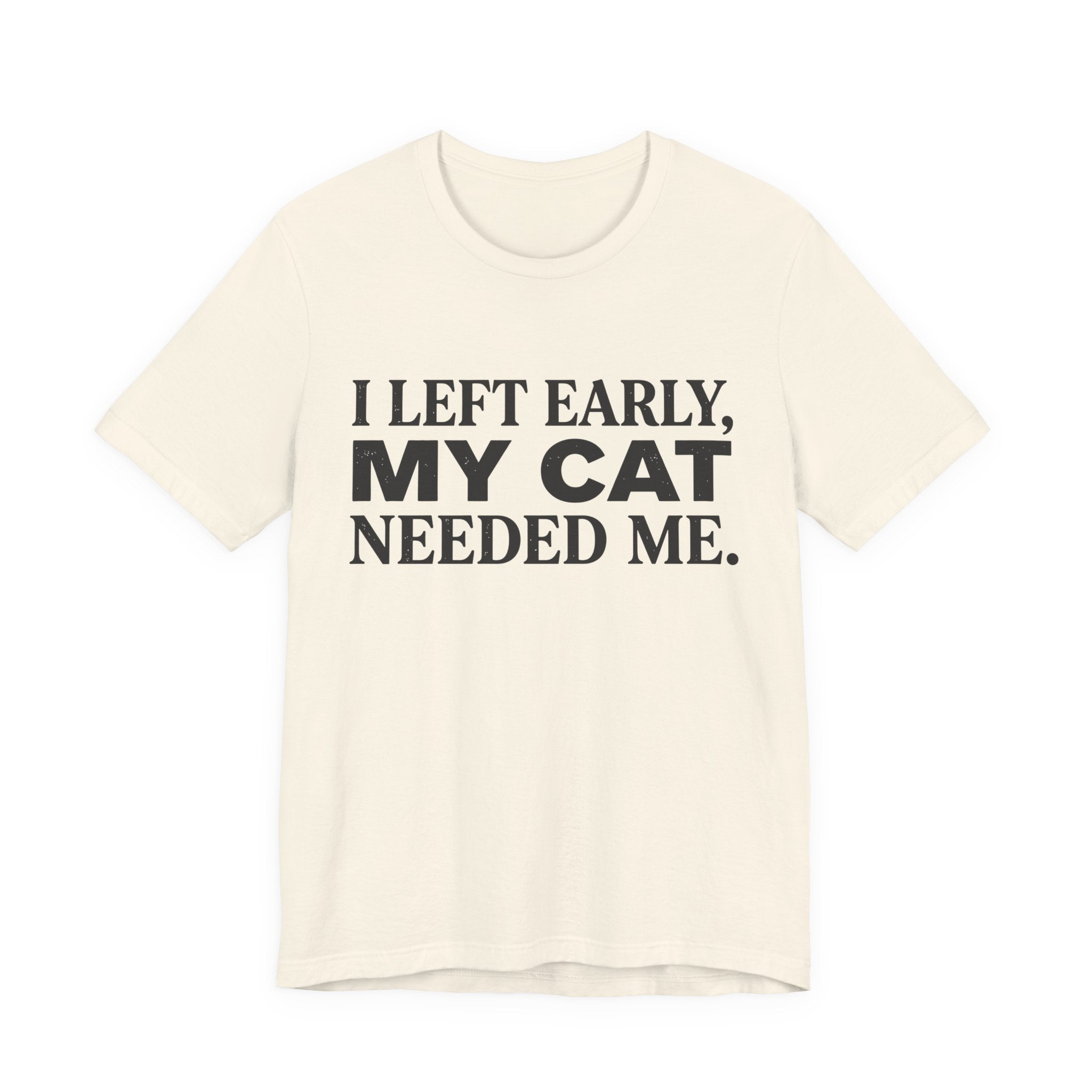 A natural short-sleeve crewneck t-shirt featuring a graphic with black text reading “I Left Early, My Cat Needed Me” arranged in three bold lines
