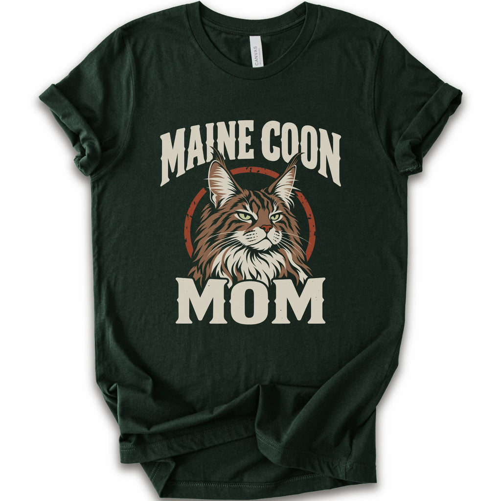 A forest short-sleeve crewneck t-shirt featuring a graphic print of a Maine Coon cat with the text 'MAINE COON MOM' in distressed cream lettering.