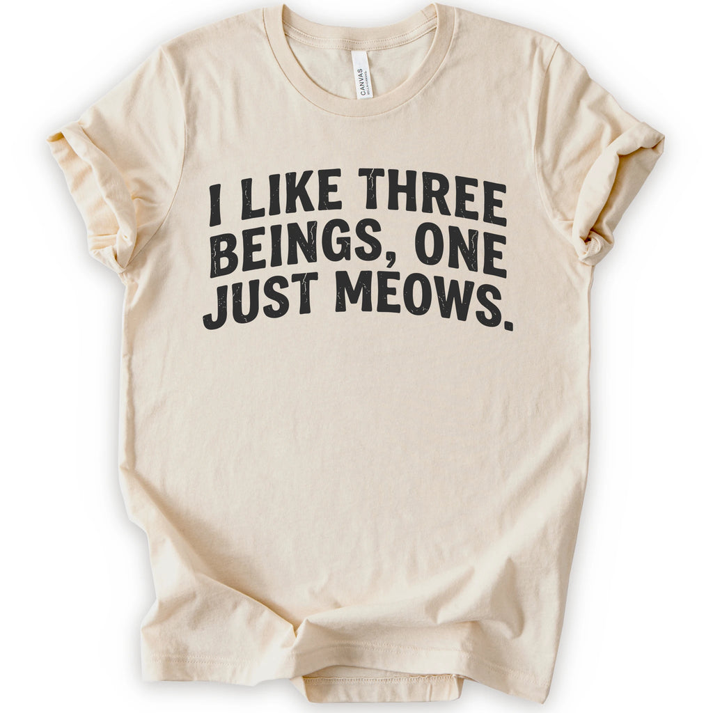 Natural graphic t-shirt with distressed black text reading “I LIKE THREE BEINGS, ONE JUST MEOWS.” for an introvert cat T-shirt