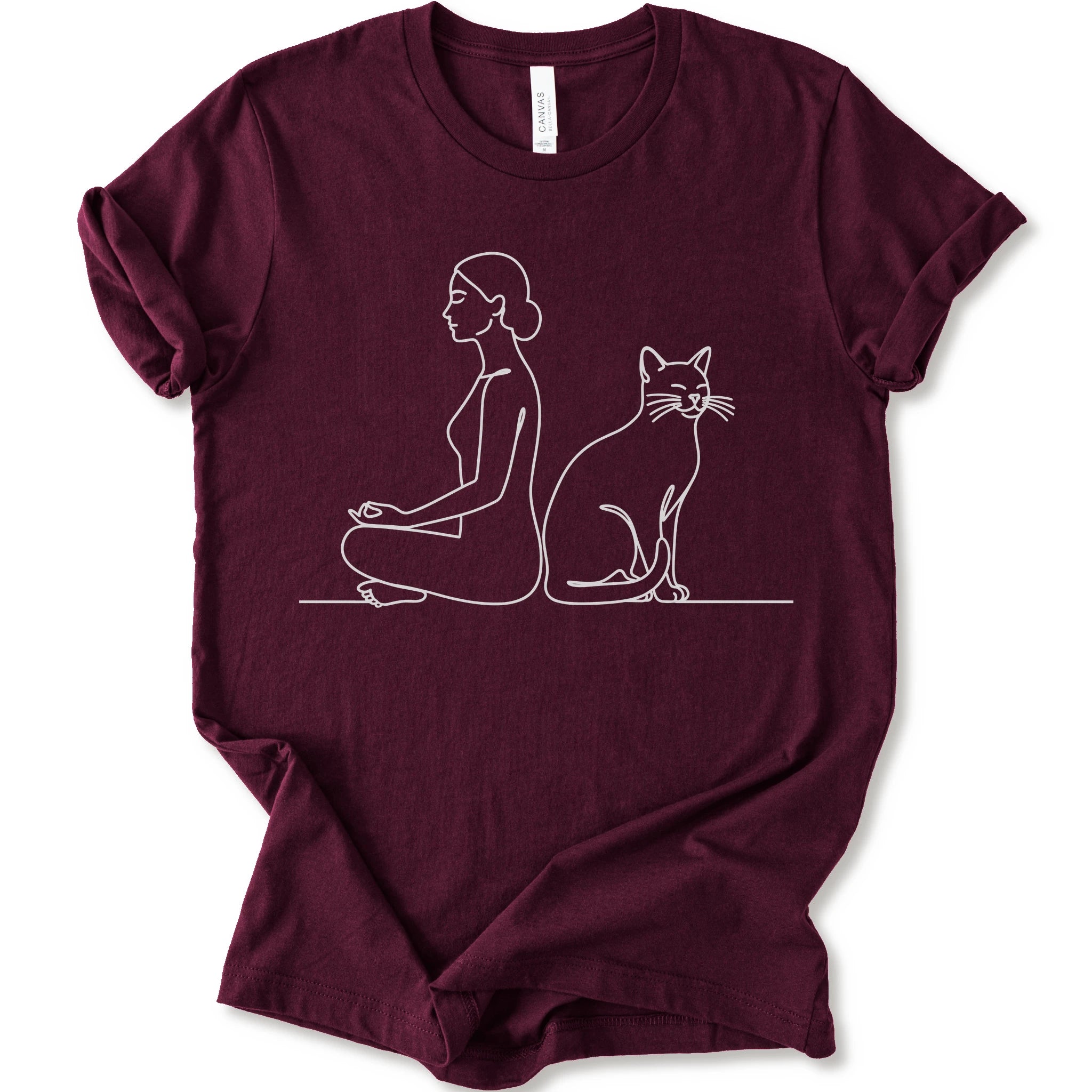 A maroon short-sleeve crewneck t-shirt with a minimalist white line art graphic of a woman in a meditation pose next to a cat.
