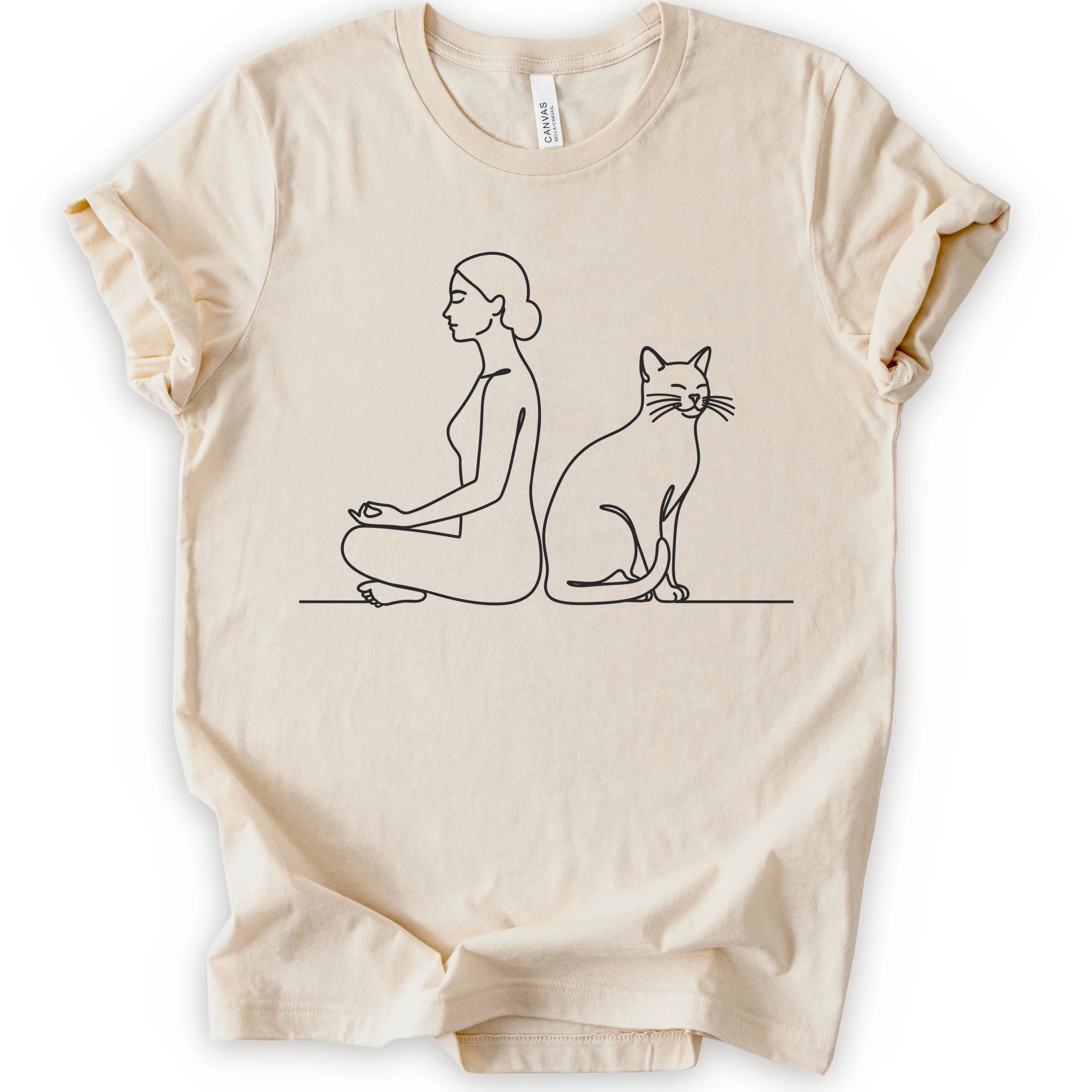 A natural short-sleeve crewneck t-shirt with a minimalist black line art graphic of a woman in a meditation pose next to a cat.