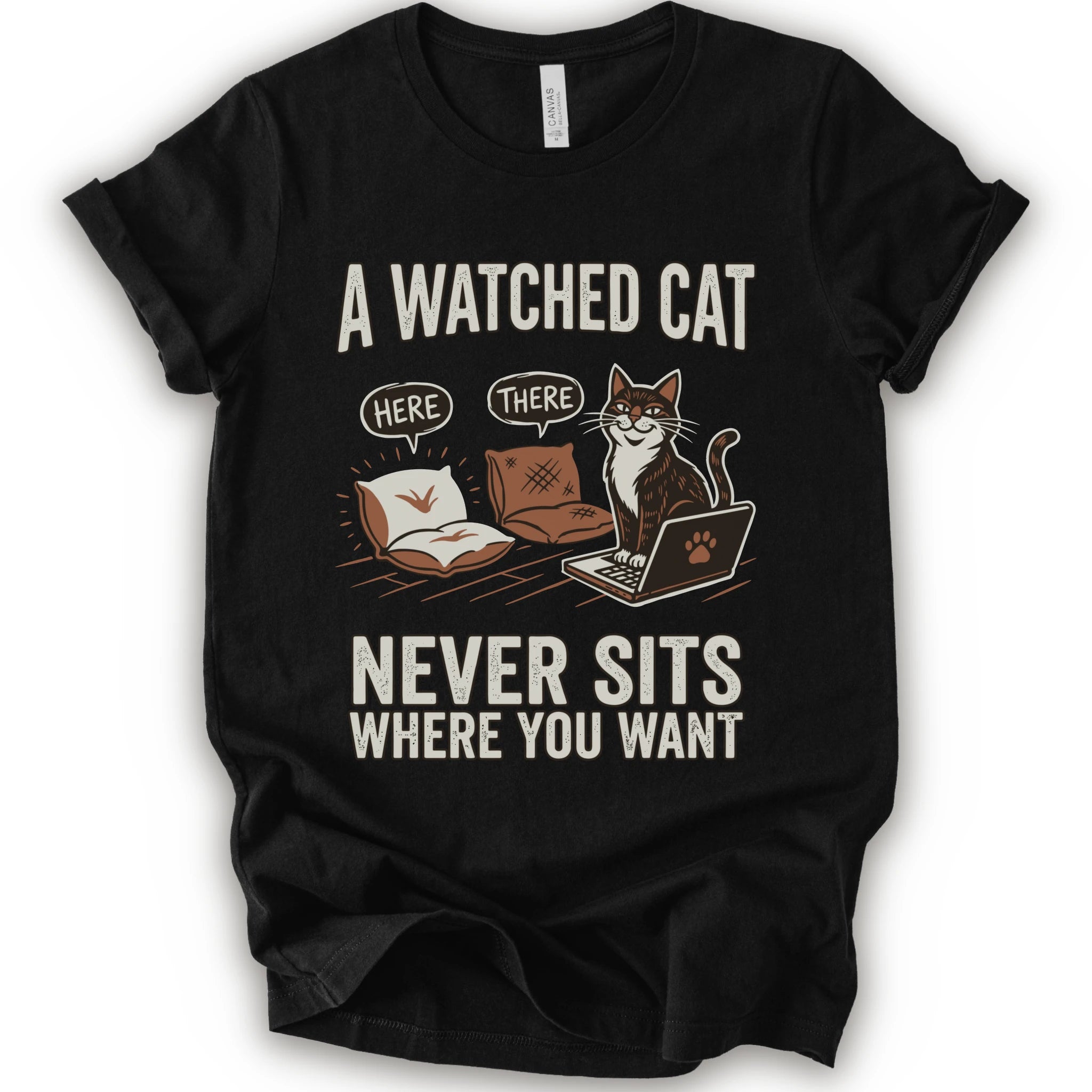 A black short-sleeve crewneck t-shirt with a humorous graphic print of a cat on a laptop and couch, featuring the text 'A WATCHED CAT NEVER SITS WHERE YOU WANT' and speech bubbles reading 'HERE' and 'THERE'.