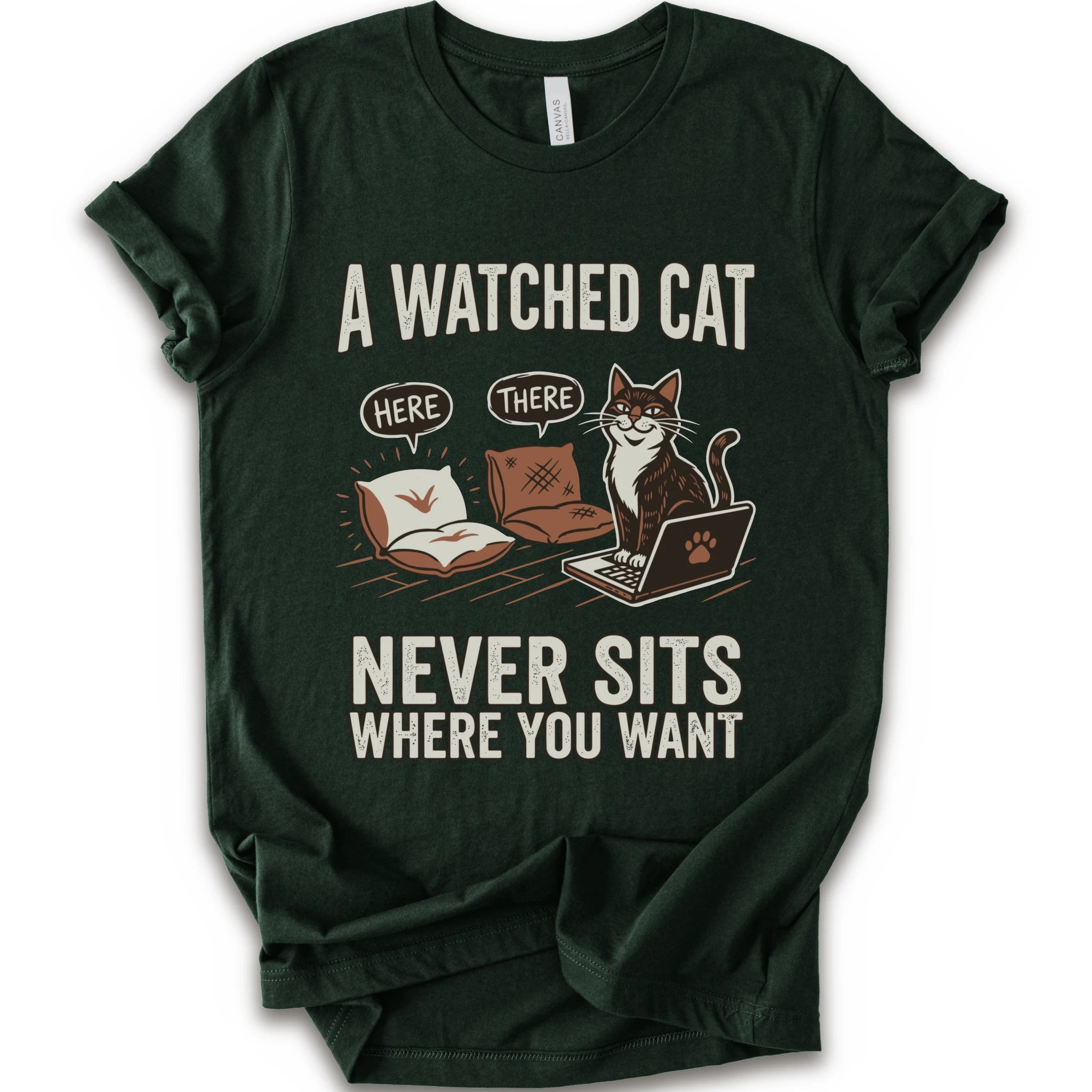 A forest short-sleeve crewneck t-shirt with a humorous graphic print of a cat on a laptop and couch, featuring the text 'A WATCHED CAT NEVER SITS WHERE YOU WANT' and speech bubbles reading 'HERE' and 'THERE'.