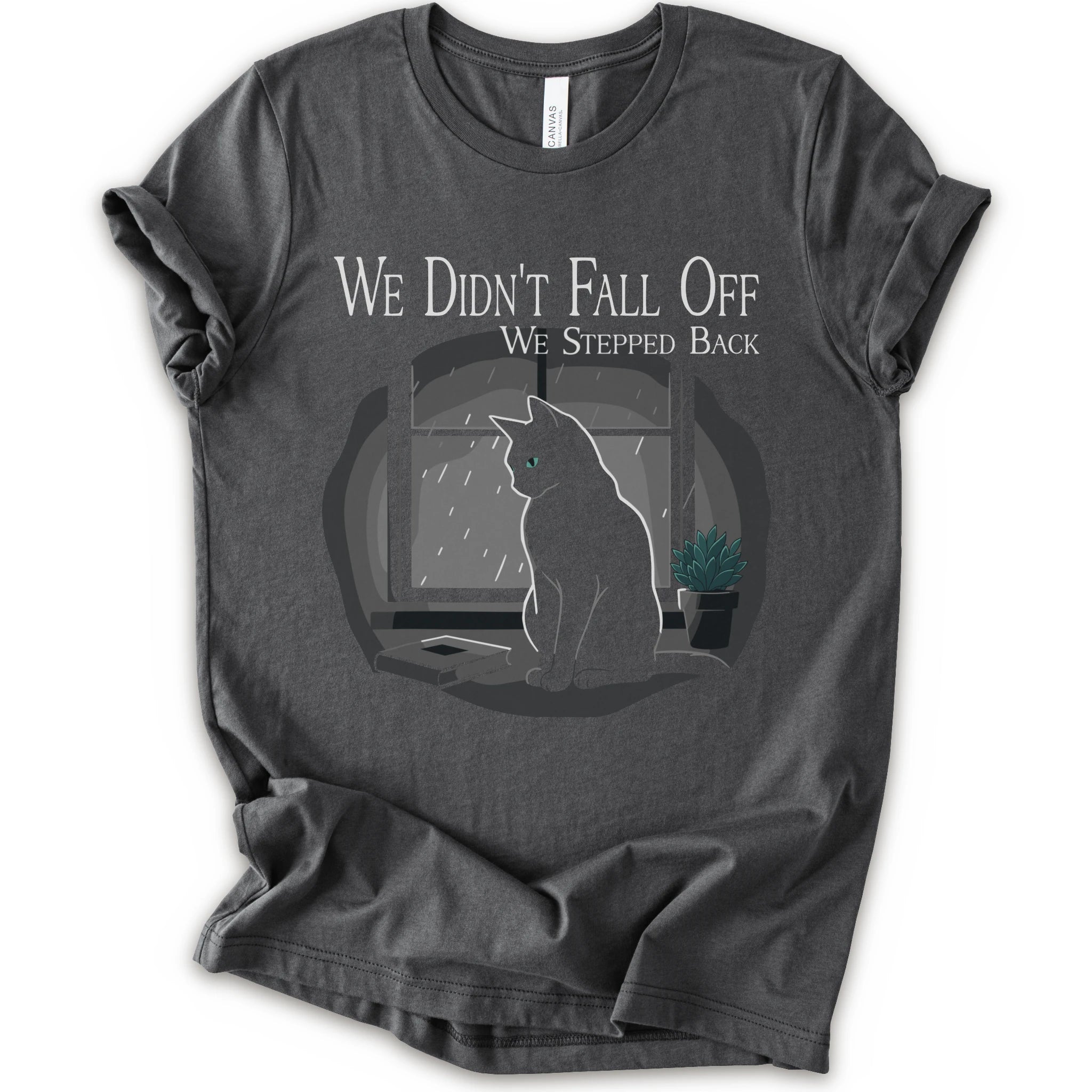 A asphalt short-sleeve crewneck t-shirt with a graphic print of a black cat sitting in front of a window with the text 'WE DIDN'T FALL OFF WE STEPPED BACK'.