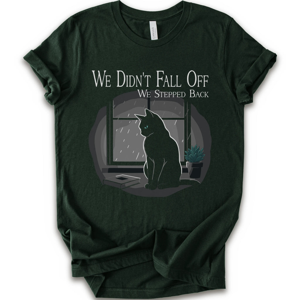 A forest short-sleeve crewneck t-shirt with a graphic print of a black cat sitting in front of a window with the text 'WE DIDN'T FALL OFF WE STEPPED BACK'.
