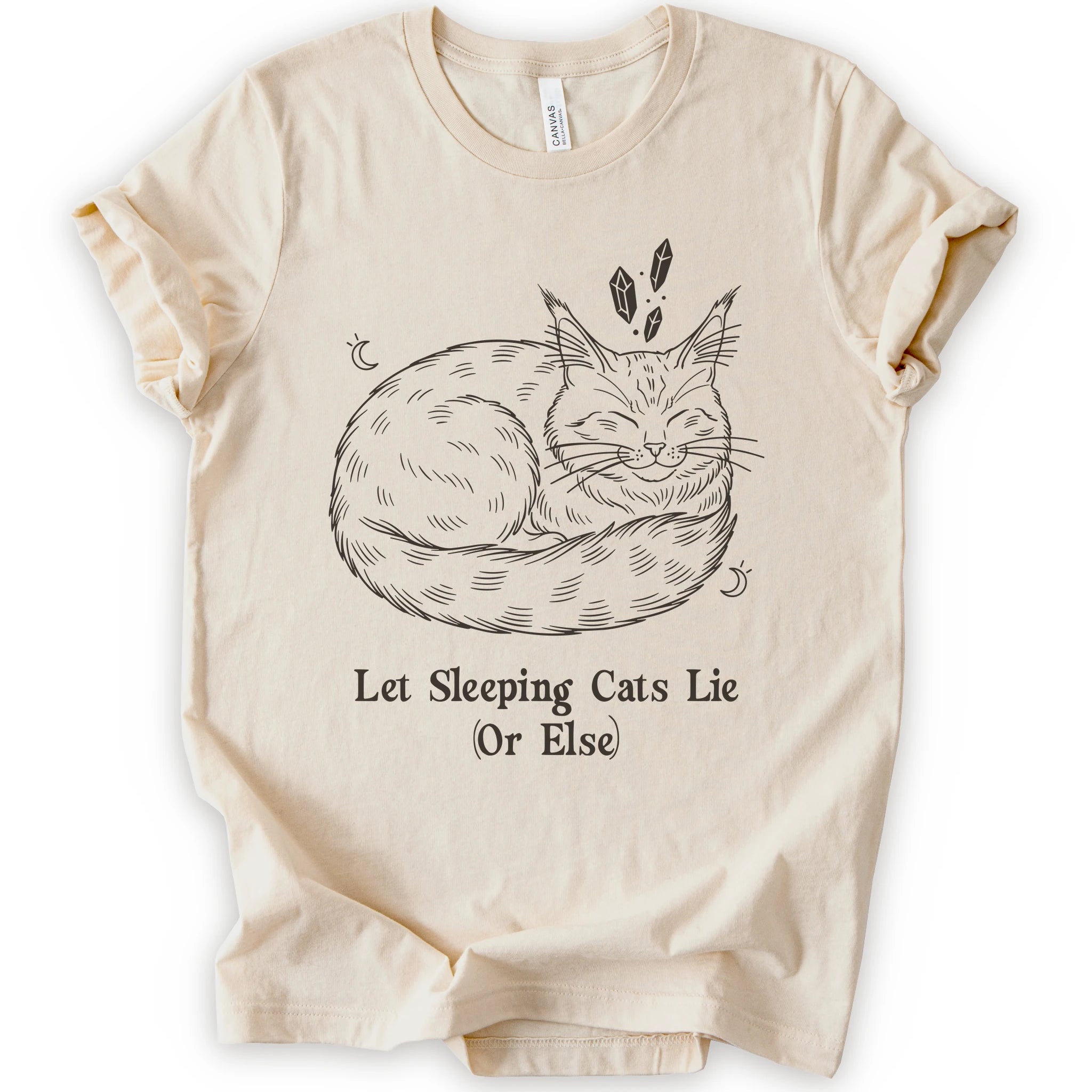 A natural short-sleeve crewneck t-shirt with a graphic of a sleeping maine coon cat in black line art, accompanied by the text 'Let Sleeping Cats Lie (Or Else)'.