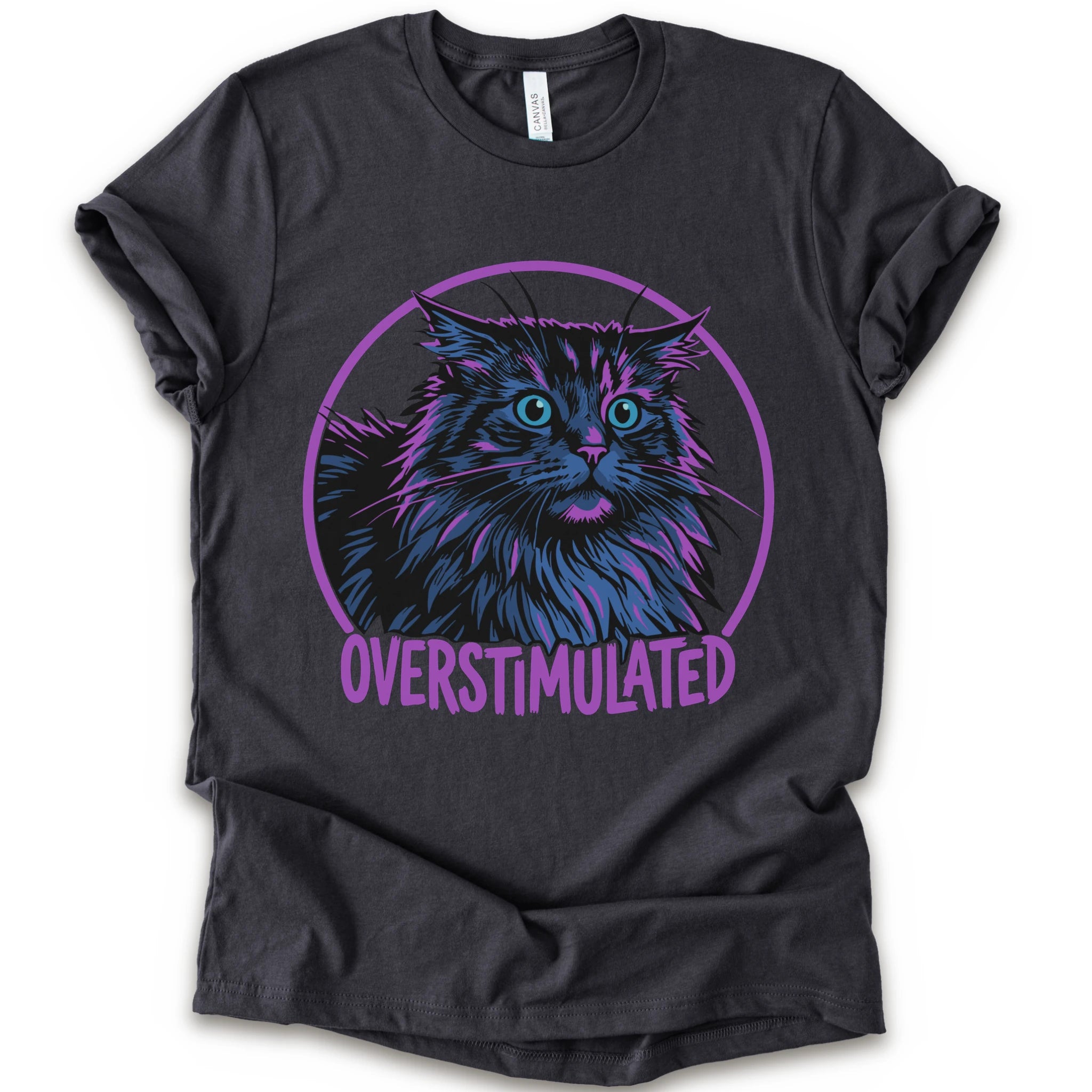 A dark grey short-sleeve crewneck t-shirt featuring a graphic of a fluffy blue and purple maine coon cat inside a purple circle with the text 'OVERSTIMULATED' in purple below it.