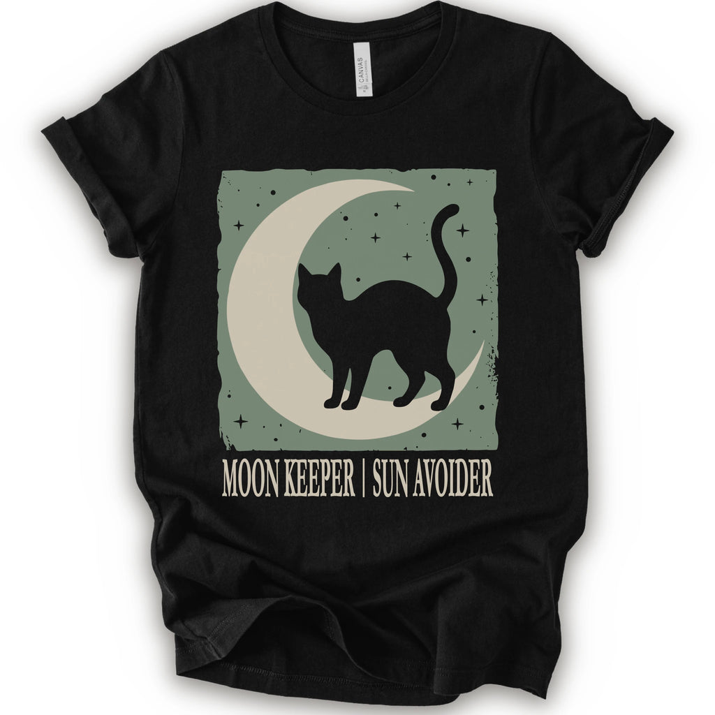 A black short-sleeve crewneck t-shirt with a graphic print of a black cat silhouette walking on a crescent moon against a sage green starry background, with the text 'MOON KEEPER | SUN AVOIDER' printed below.