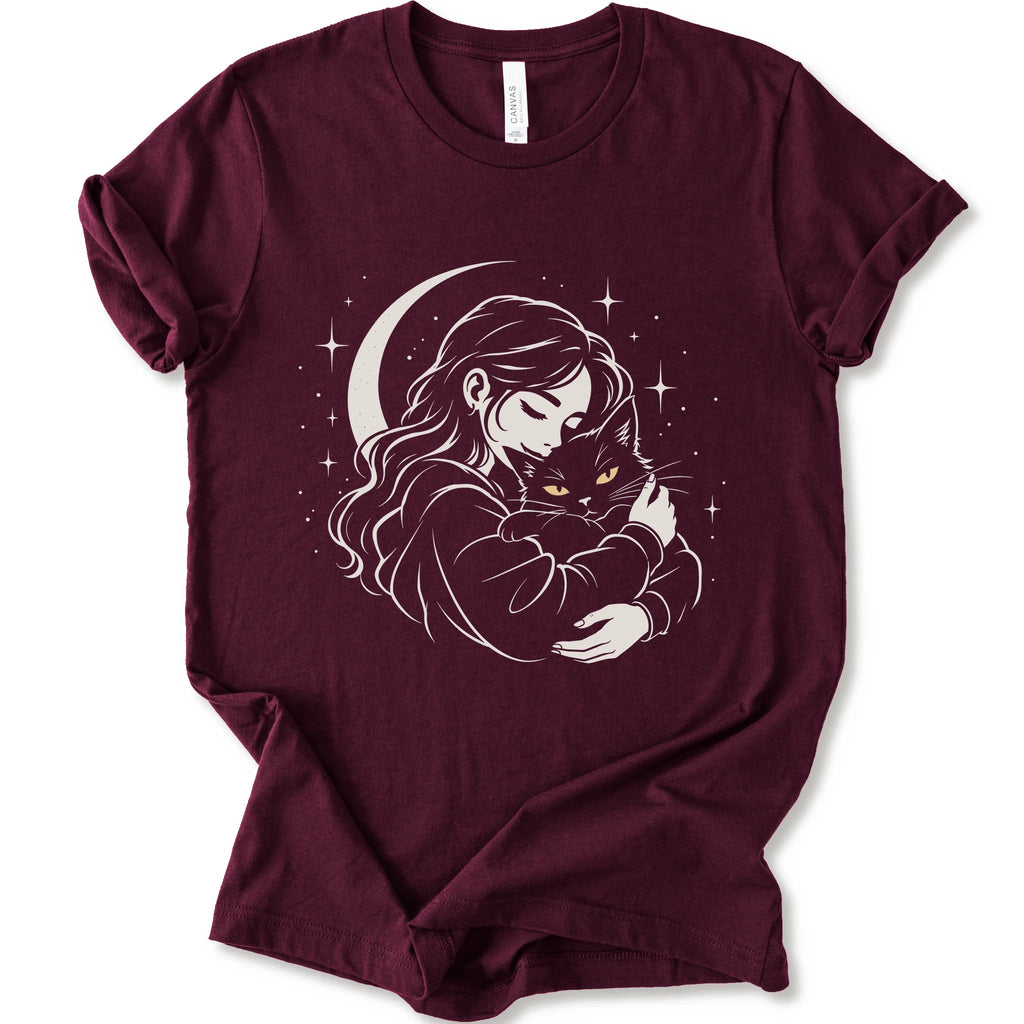 Maroon graphic t-shirt with a woman hugging a fluffy cat beneath a crescent moon and stars, drawn in cream lines with golden cat eyes