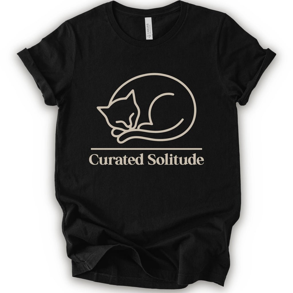 A black short-sleeve crewneck t-shirt with a cream-colored graphic of a curled-up sleeping cat, with the text 'Curated Solitude' printed below.