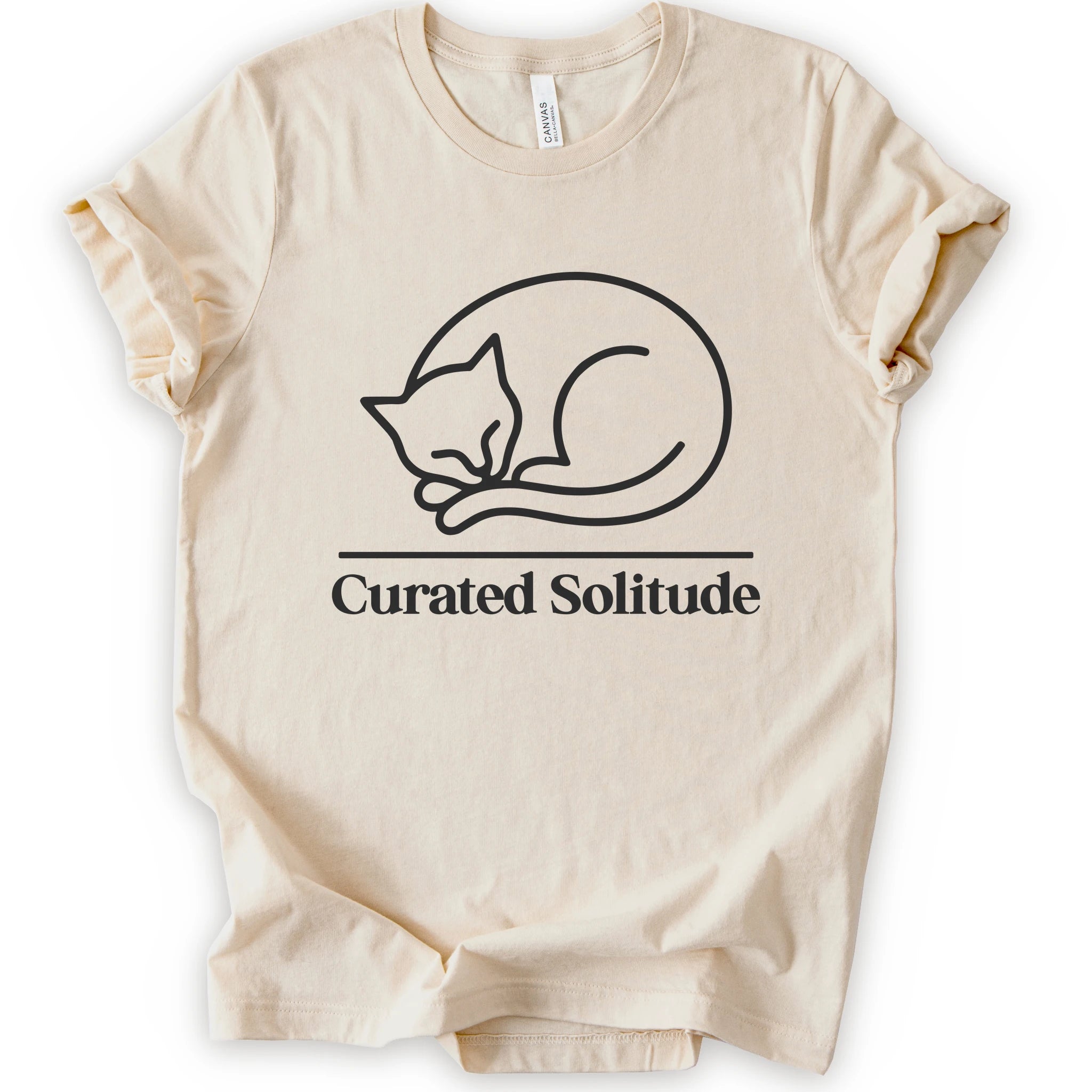 A natural short-sleeve crewneck t-shirt with a black-colored graphic of a curled-up sleeping cat, with the text 'Curated Solitude' printed below.