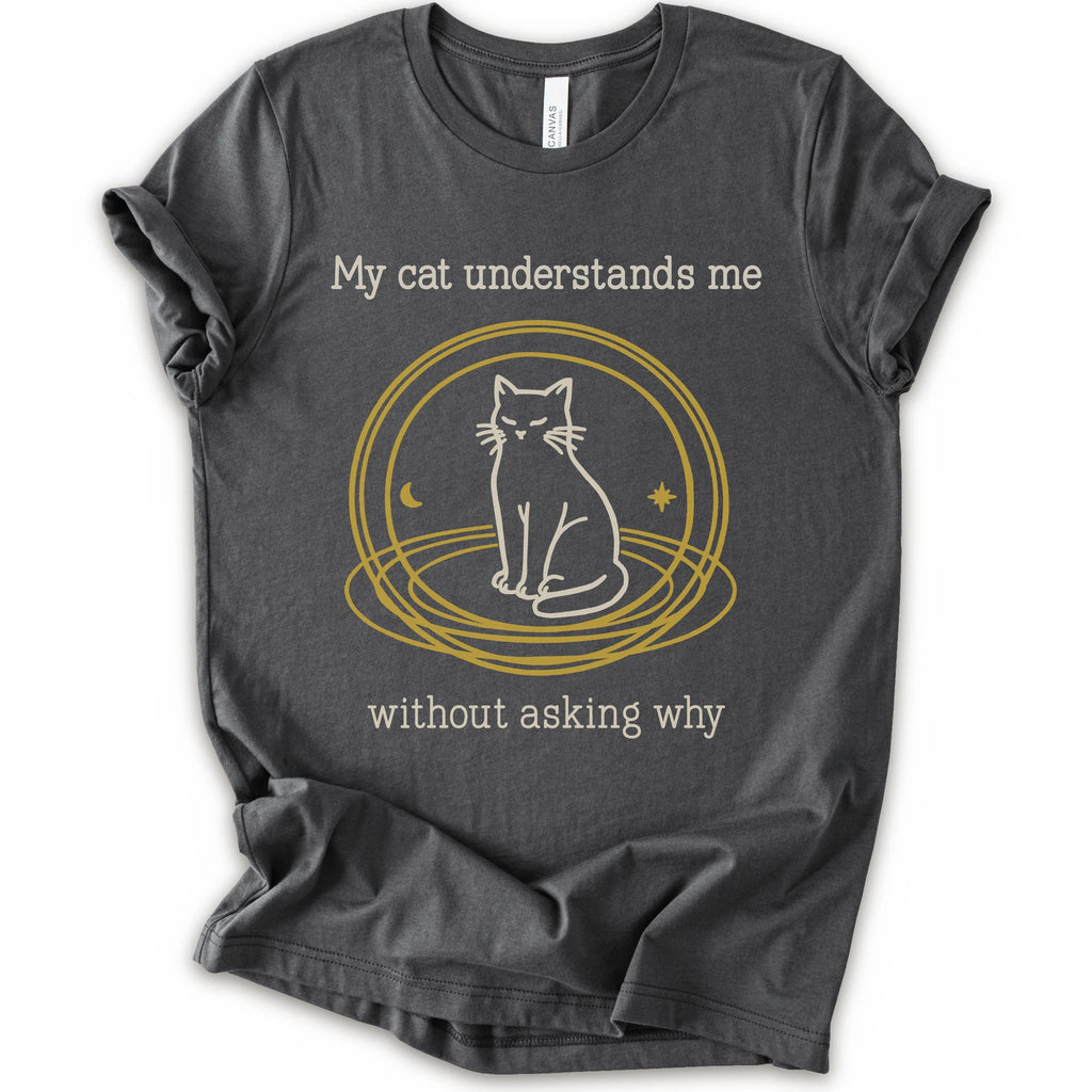 A asphalt t-shirt with a graphic of a white cat sitting inside a gold circular frame, with the text 'My cat understands me without asking why' in a light beige font.