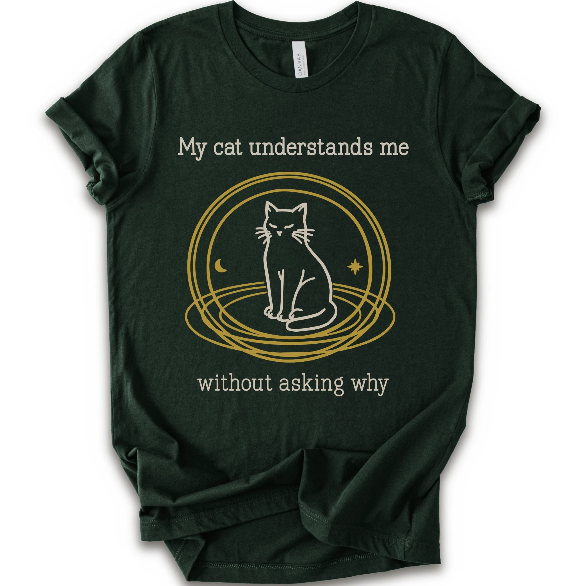 A forest t-shirt with a graphic of a white cat sitting inside a gold circular frame, with the text 'My cat understands me without asking why' in a light beige font.
