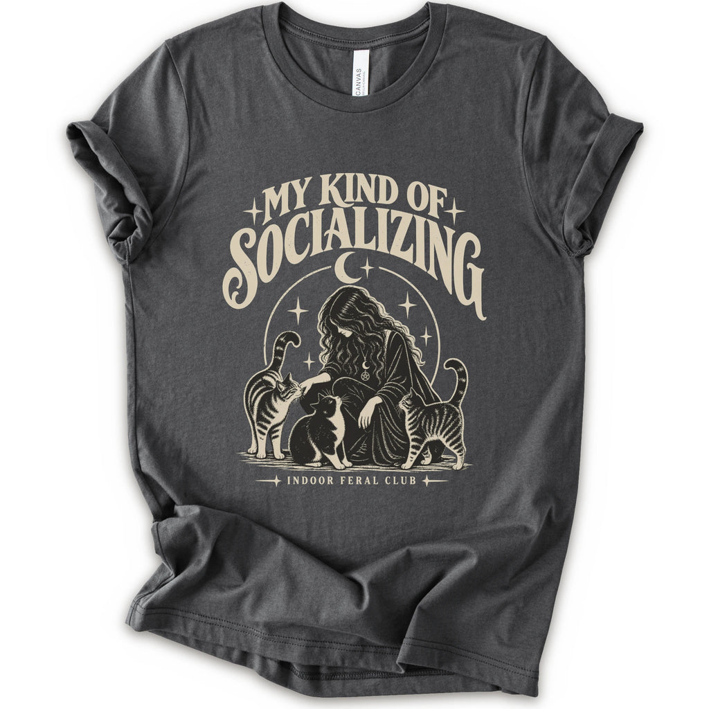 An asphalt short-sleeve t-shirt with a cream-colored graphic print on the front. The graphic features the text 'MY KIND OF SOCIALIZING' in a stylized font above an illustration of a woman surrounded by cats under a crescent moon, with 'INDOOR FERAL CLUB' printed below.