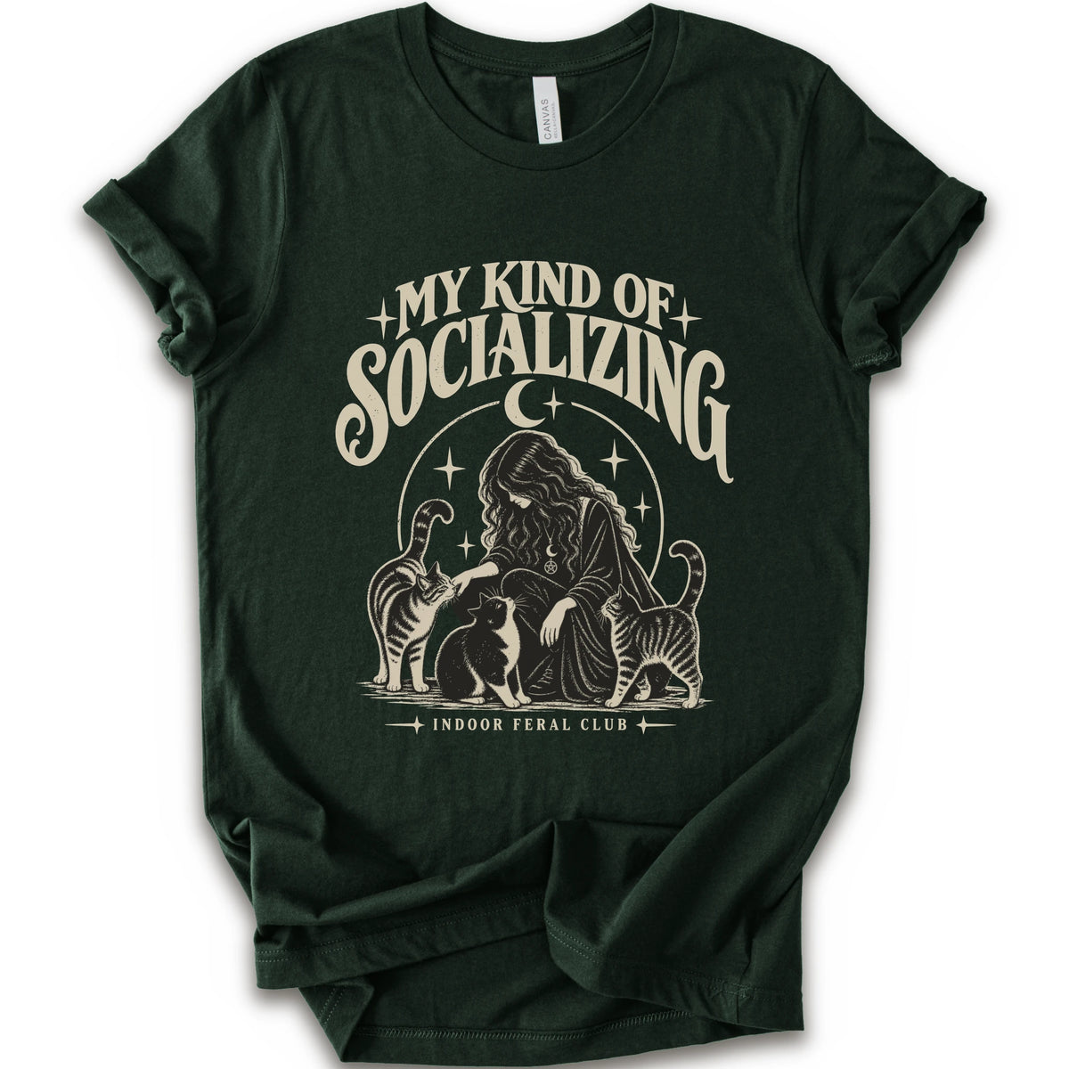 A forest short-sleeve t-shirt with a cream-colored graphic print on the front. The graphic features the text 'MY KIND OF SOCIALIZING' in a stylized font above an illustration of a woman surrounded by cats under a crescent moon, with 'INDOOR FERAL CLUB' printed below.