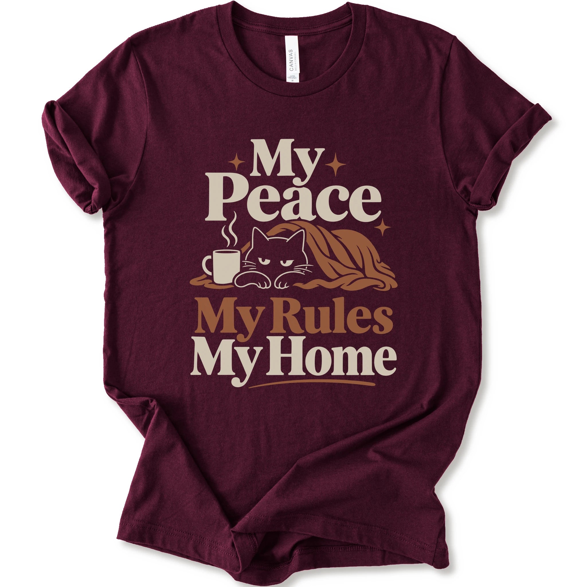A maroon short-sleeve crewneck t-shirt with a retro-style graphic print that reads 'My Peace My Rules My Home' in cream and brown text, featuring an illustration of a black cat under a brown blanket next to a small mug.