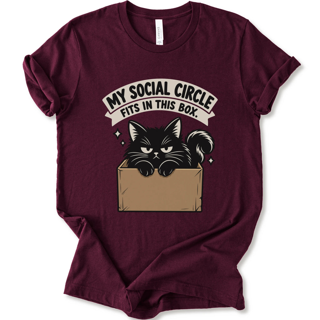 A maroon short-sleeve crewneck t-shirt with a graphic print of a black cat in a cardboard box and the text 'MY SOCIAL CIRCLE FITS IN THIS BOX."
