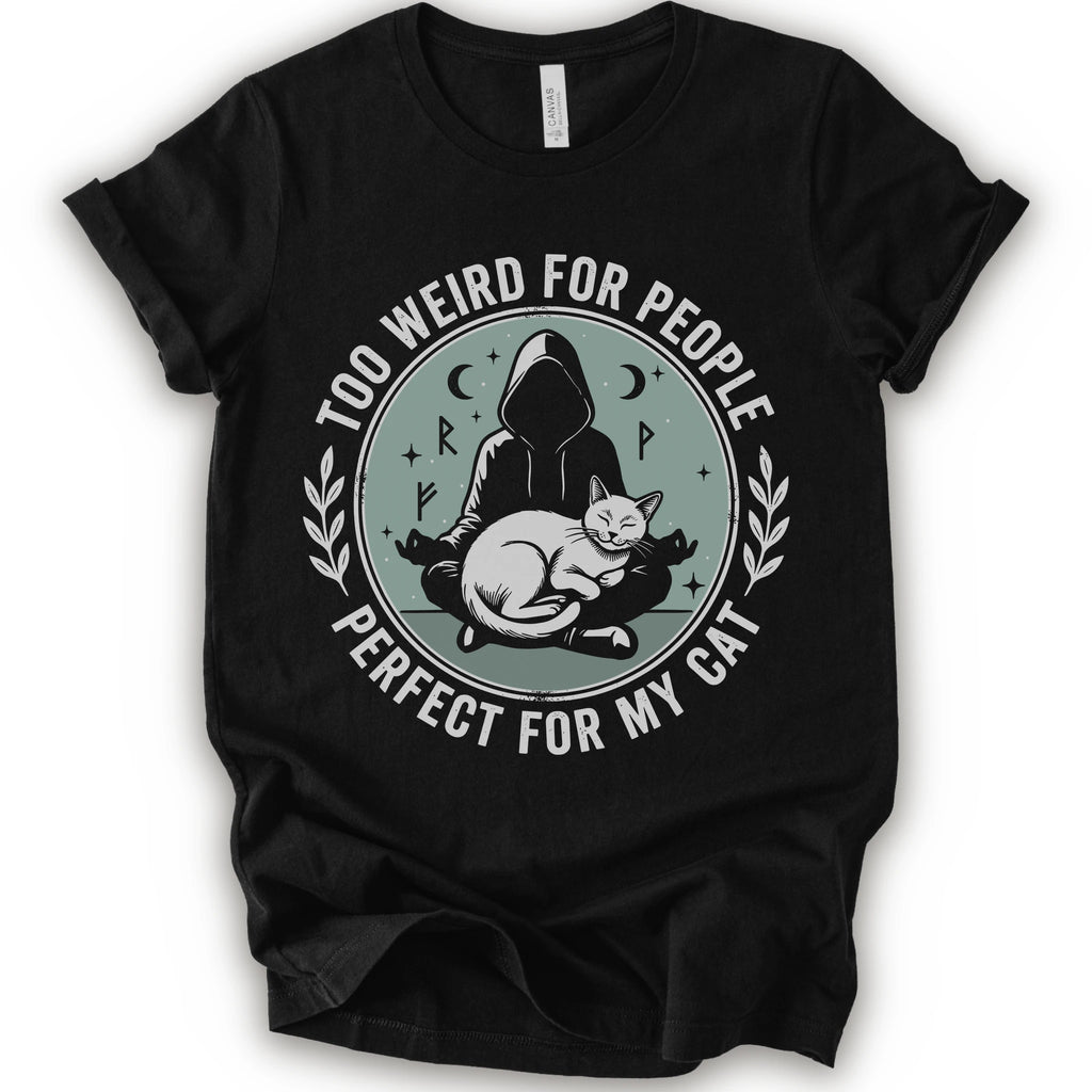 A black short-sleeve crewneck t-shirt with a circular graphic on the front. The graphic features a dark silhouette of a person in a hood sitting cross-legged next to a white cat, surrounded by the text 'TOO WEIRD FOR PEOPLE' on top and 'PERFECT FOR MY CAT' on the bottom, with small moon and star details.