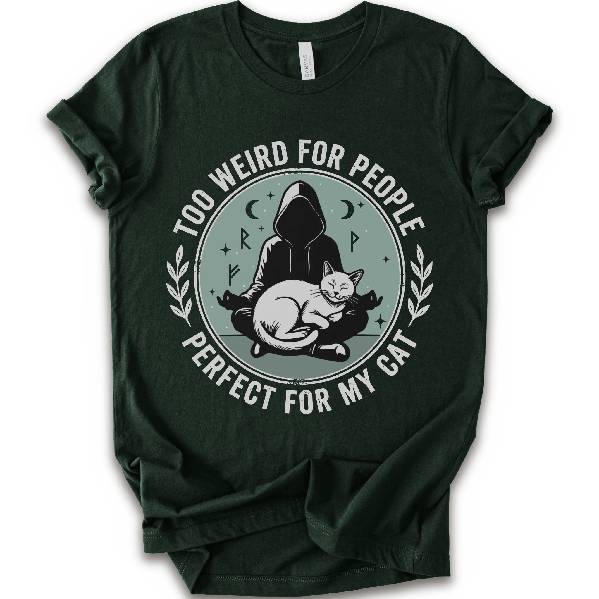 A forest short-sleeve crewneck t-shirt with a circular graphic on the front. The graphic features a dark silhouette of a person in a hood sitting cross-legged next to a white cat, surrounded by the text 'TOO WEIRD FOR PEOPLE' on top and 'PERFECT FOR MY CAT' on the bottom, with small moon and star details.