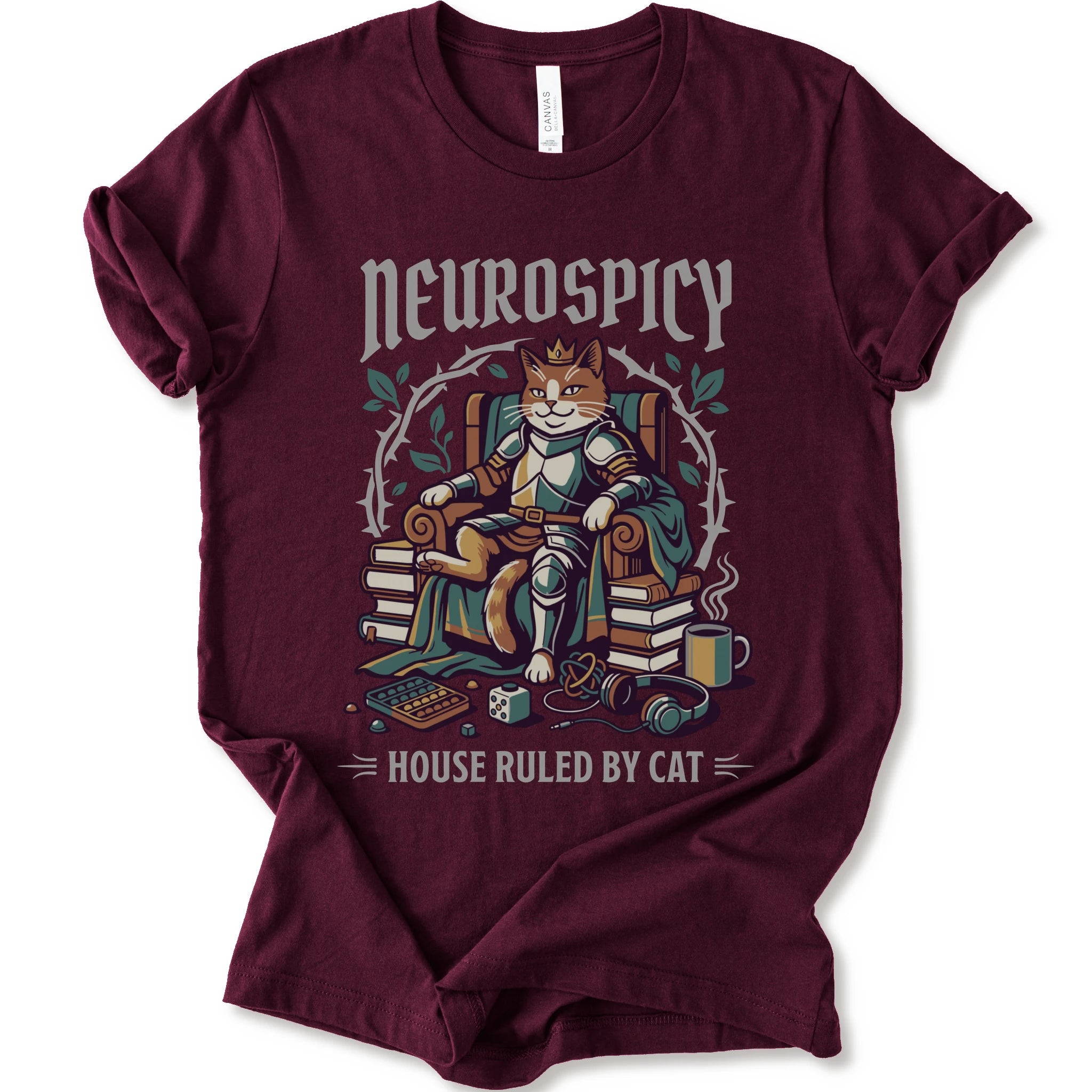A maroon short-sleeve crewneck t-shirt featuring a graphic of a cat dressed in medieval armor sitting on a throne, surrounded by books, with the text 'Neurospicy' above and 'House Ruled By Cat' below.