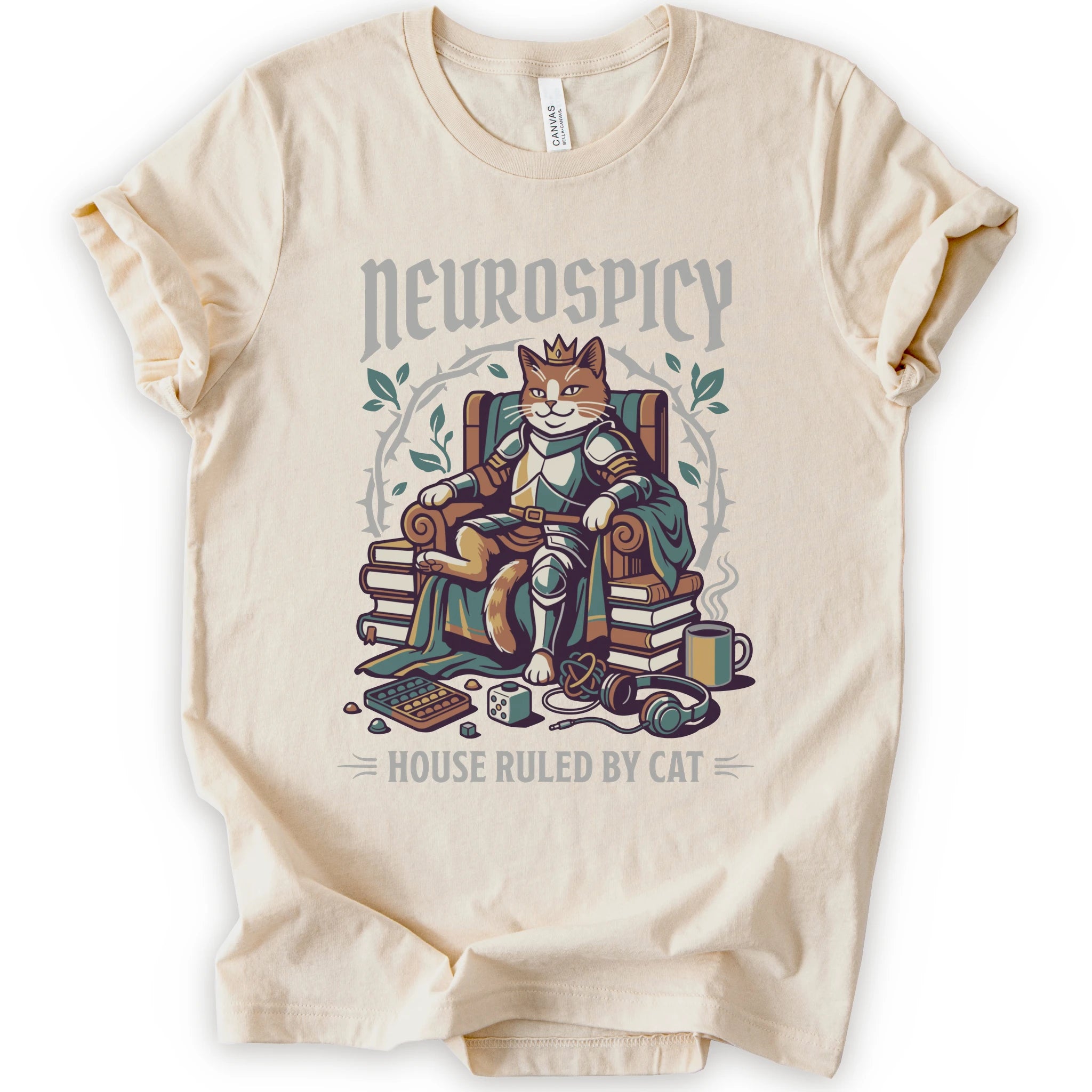 A natural short-sleeve crewneck t-shirt featuring a graphic of a cat dressed in medieval armor sitting on a throne, surrounded by books, with the text 'Neurospicy' above and 'House Ruled By Cat' below.