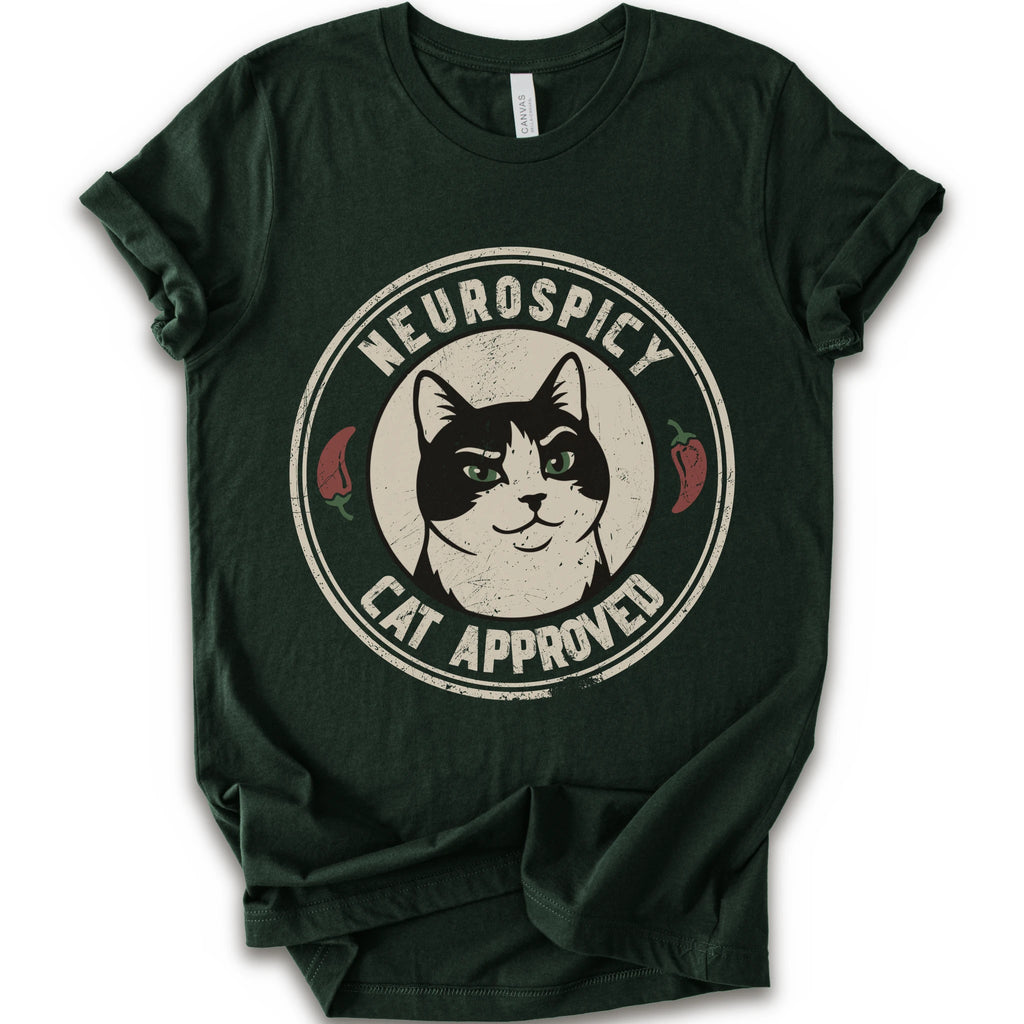 A forest short-sleeve crewneck t-shirt with a distressed circular graphic on the chest featuring a black and white cat with green eyes, red peppers, and the text 'NEUROSPICY, CAT APPROVED'.