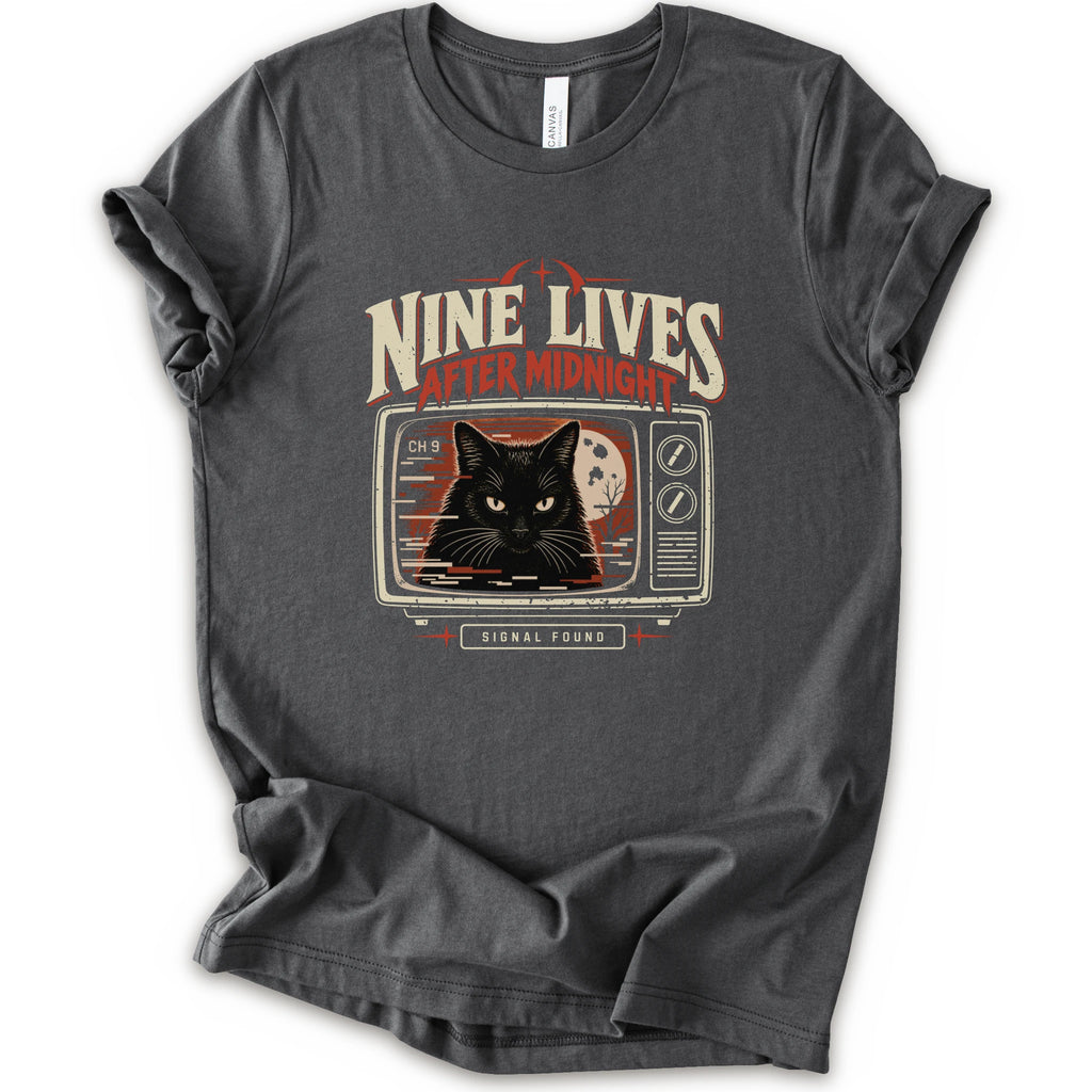 An asphalt short-sleeve crewneck t-shirt with a vintage-style graphic on the front. The graphic features the text 'NINE LIVES AFTER MIDNIGHT' in distressed cream and red lettering above an illustration of a black cat's face on a retro television screen, with 'SIGNAL FOUND' written below.