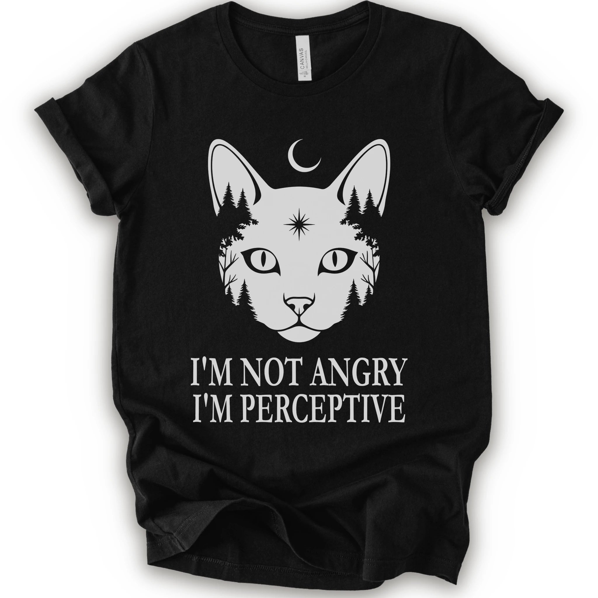 A black short-sleeve crewneck t-shirt with a white graphic of a cat's face containing pine trees and a crescent moon, with the text 'I'M NOT ANGRY I'M PERCEPTIVE' printed below.