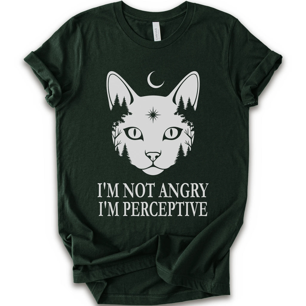 A forest short-sleeve crewneck t-shirt with a white graphic of a cat's face containing pine trees and a crescent moon, with the text 'I'M NOT ANGRY I'M PERCEPTIVE' printed below.