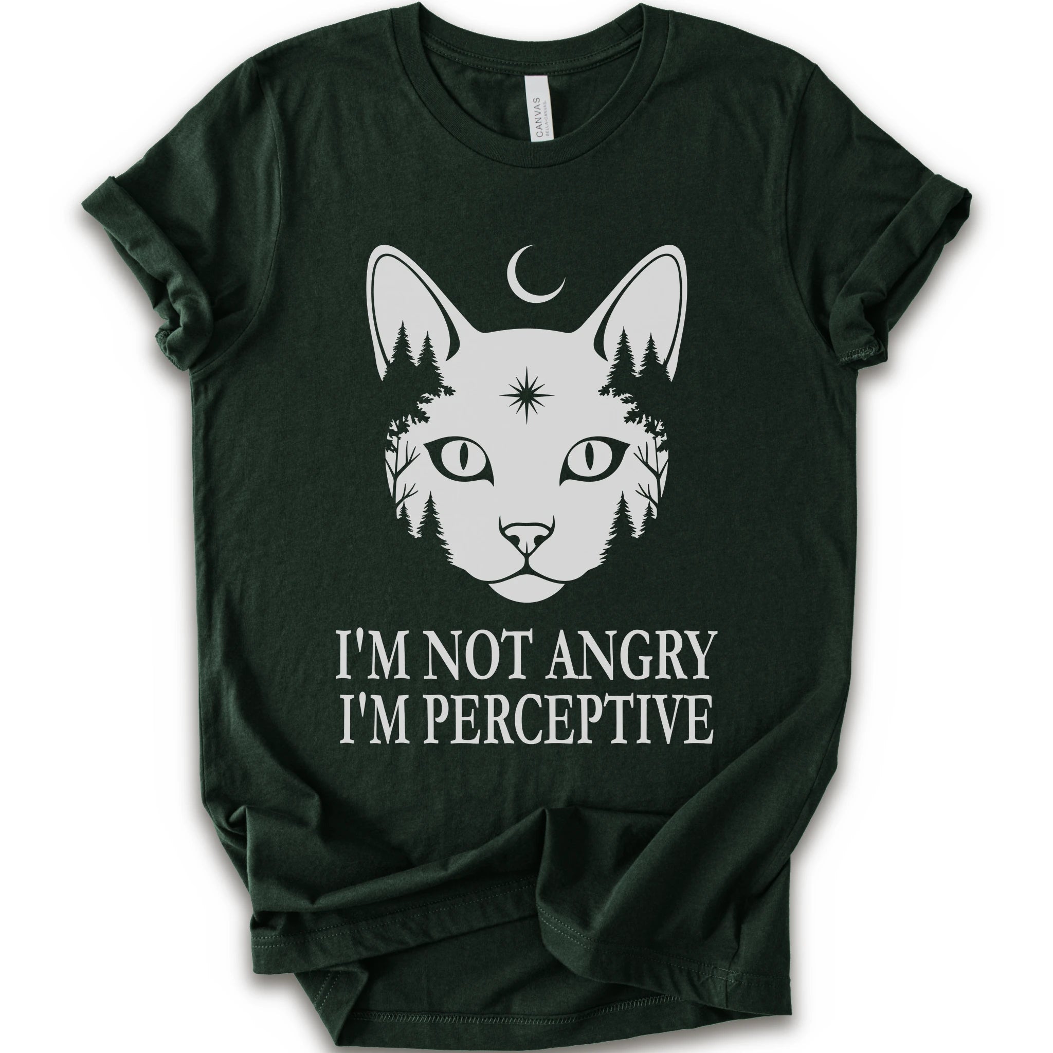 A forest short-sleeve crewneck t-shirt with a white graphic of a cat's face containing pine trees and a crescent moon, with the text 'I'M NOT ANGRY I'M PERCEPTIVE' printed below.
