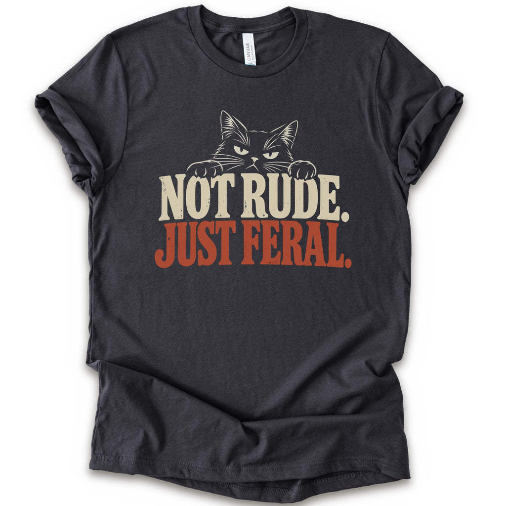 A dark grey short-sleeve t-shirt with a graphic print of a cat with narrowed eyes and visible paws peers over the words “NOT RUDE.” above a large rust-colored “JUST FERAL.” The design uses bold distressed serif lettering in cream and rust with a retro graphic look.