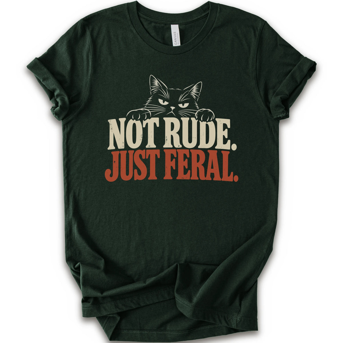 A forest short-sleeve t-shirt with a graphic print of a cat with narrowed eyes and visible paws peers over the words “NOT RUDE.” above a large rust-colored “JUST FERAL.” The design uses bold distressed serif lettering in cream and rust with a retro graphic look.