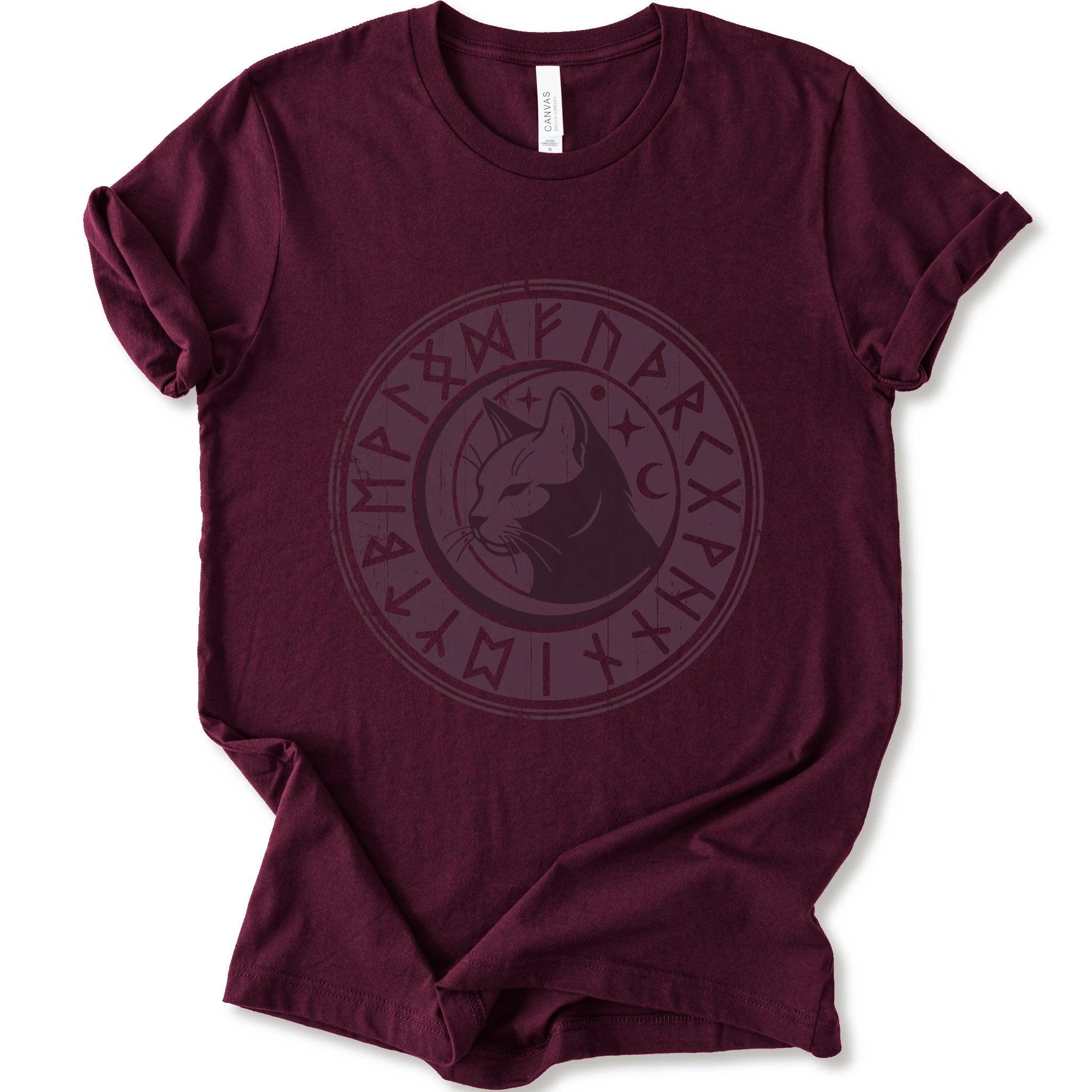A maroon short-sleeve crewneck t-shirt with a circular dark purple graphic on the chest featuring a cat's face surrounded by runic symbols.