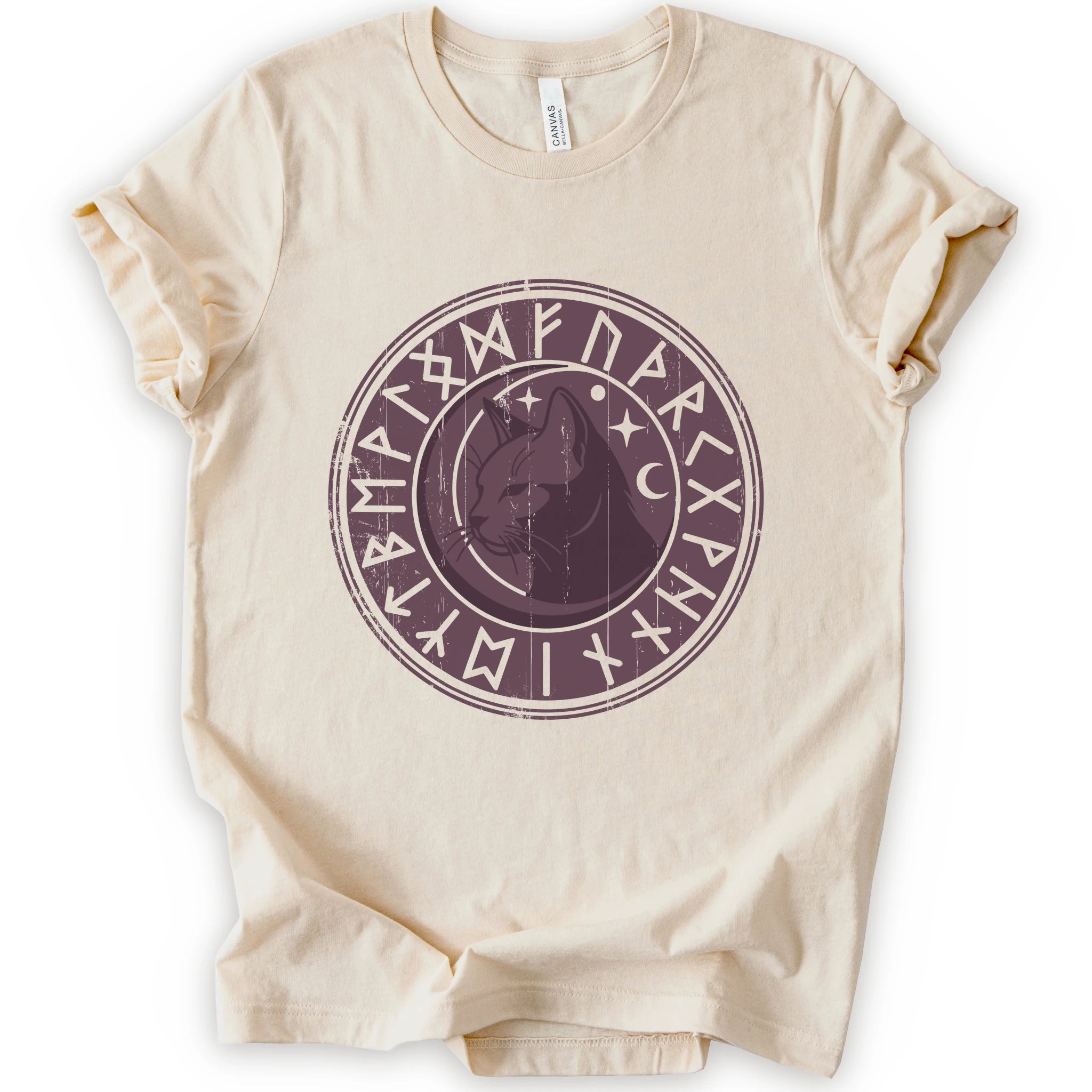 A natural short-sleeve crewneck t-shirt with a circular dark purple graphic on the chest featuring a cat's face surrounded by runic symbols.