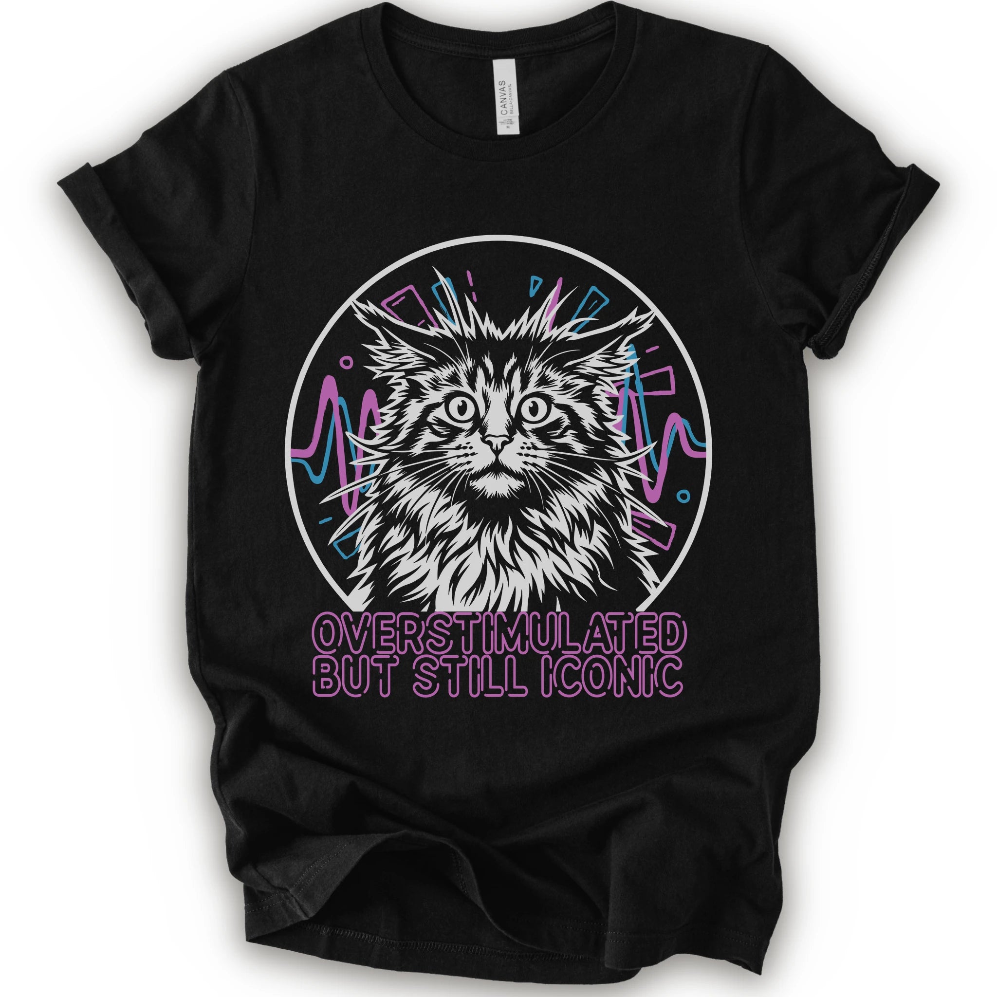 A black short-sleeve crewneck t-shirt featuring a graphic of a white and gray maine con cat inside a circular frame with pink and blue accents, and the text 'OVERSTIMULATED BUT STILL ICONIC' in pink below.
