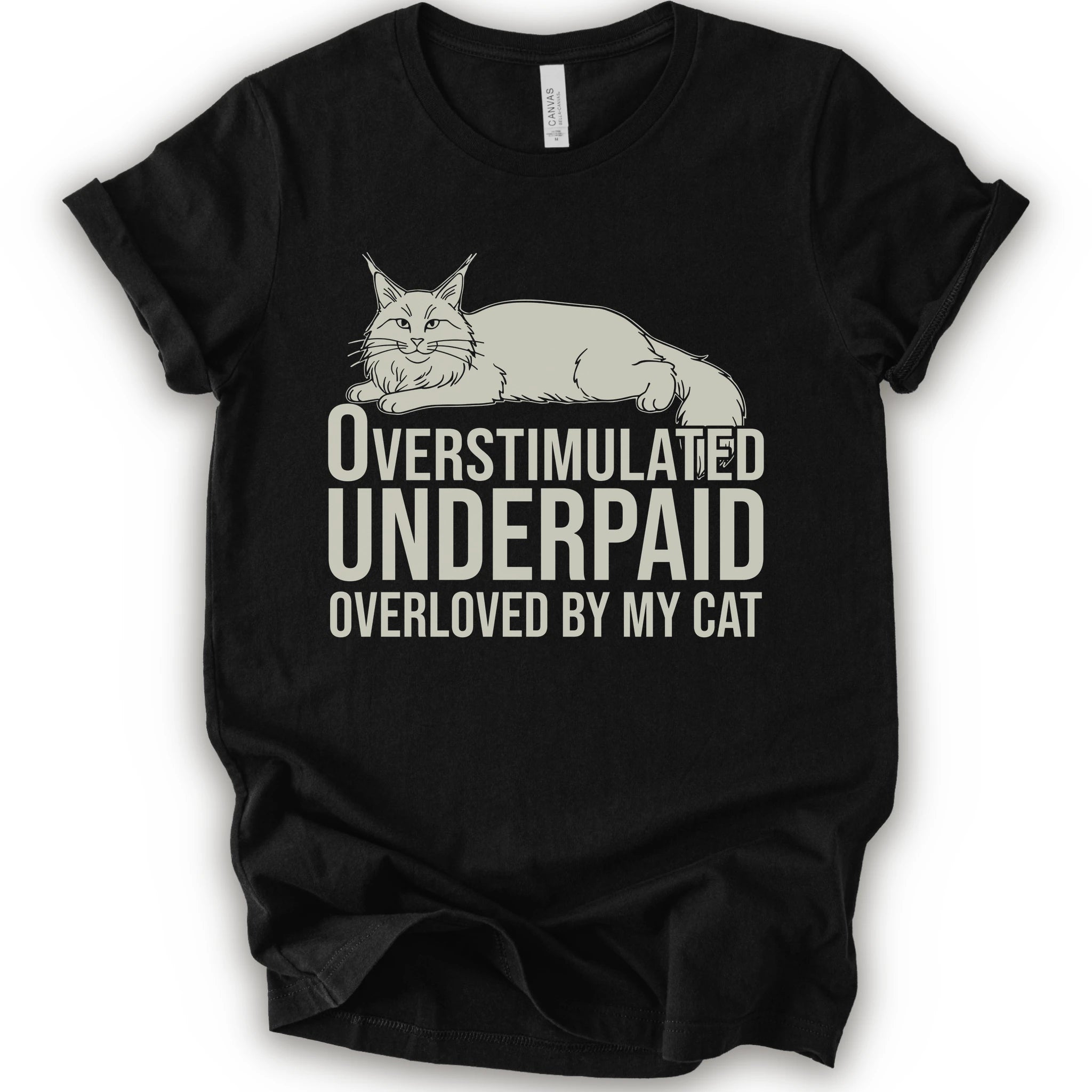 A black short-sleeve crewneck T-shirt with a lounging cat graphic and “Overstimulated, Underpaid, Overloved by My Cat” text.