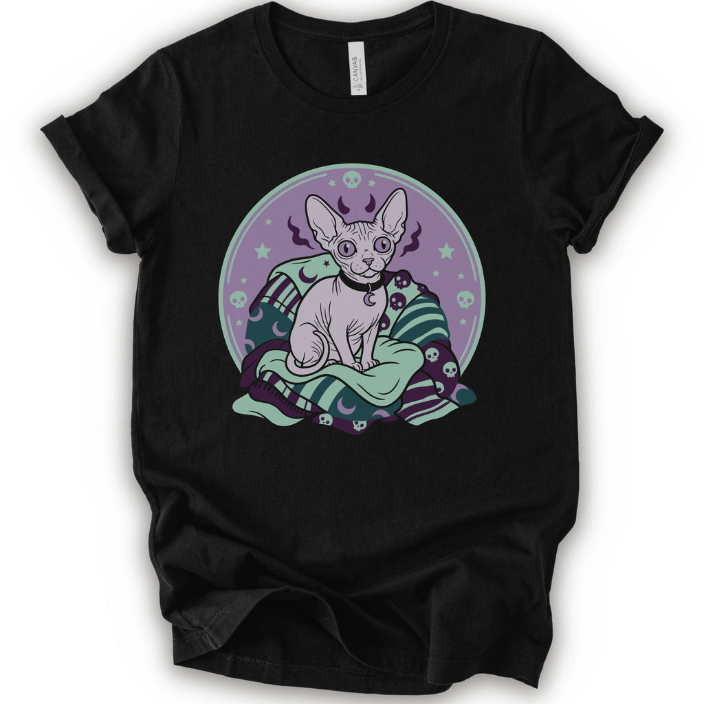 A black short-sleeve crewneck t-shirt featuring a graphic print of a hairless cat sitting on a green and purple patterned blanket inside a purple circular frame.