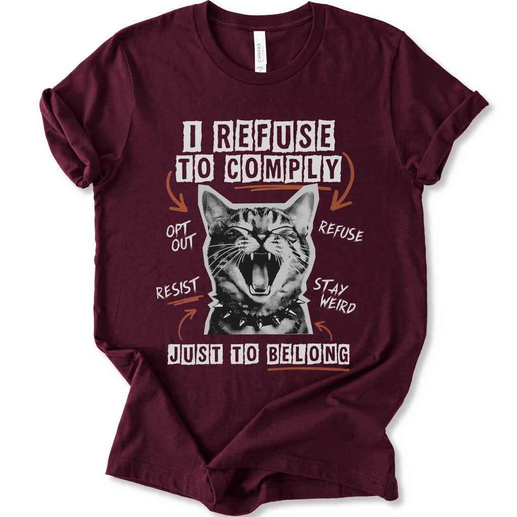A maroon short-sleeve graphic t-shirt featuring a screaming cat illustration and the text 'I REFUSE TO COMPLY' and 'JUST TO BELONG' in white and orange.