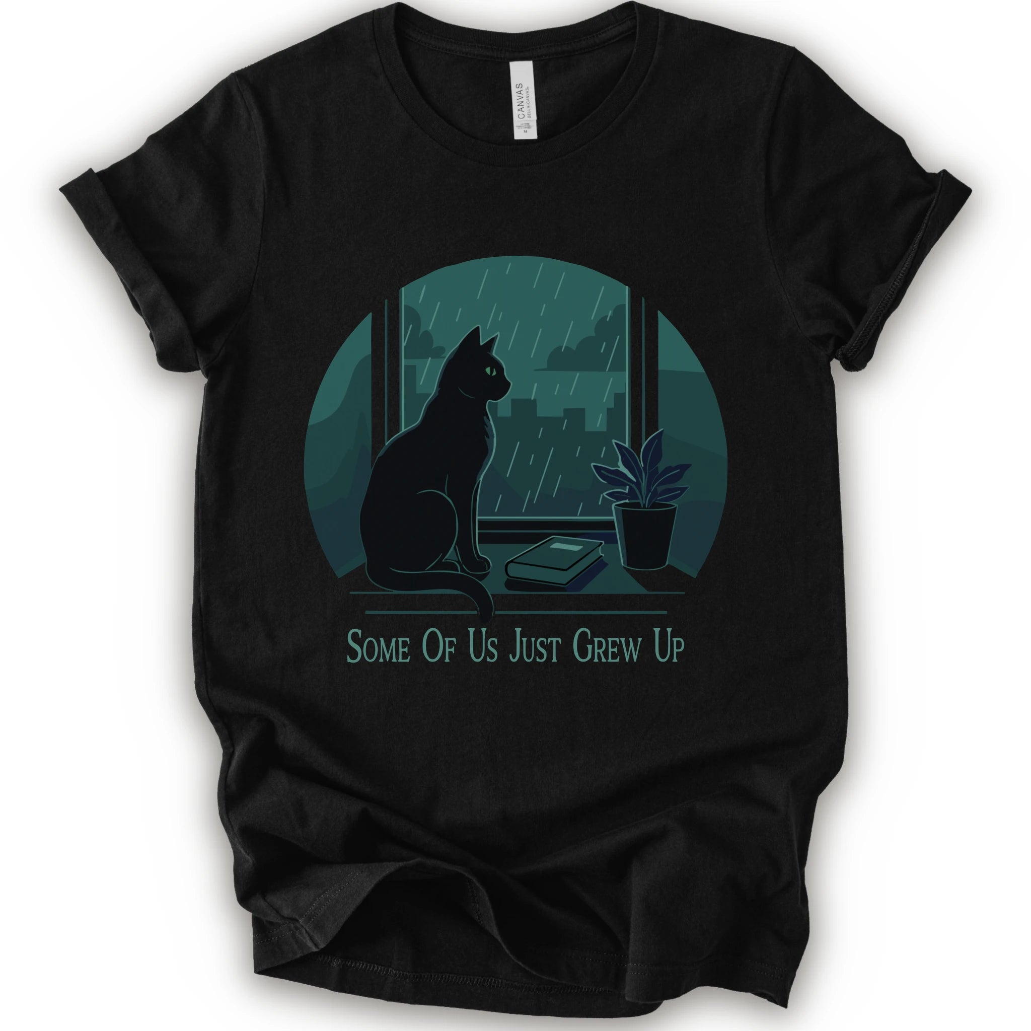 A black short-sleeve crewneck t-shirt with a graphic print of a black cat sitting by a window in the rain, next to a small potted plant, with the text 'SOME OF US JUST GREW UP' printed below.