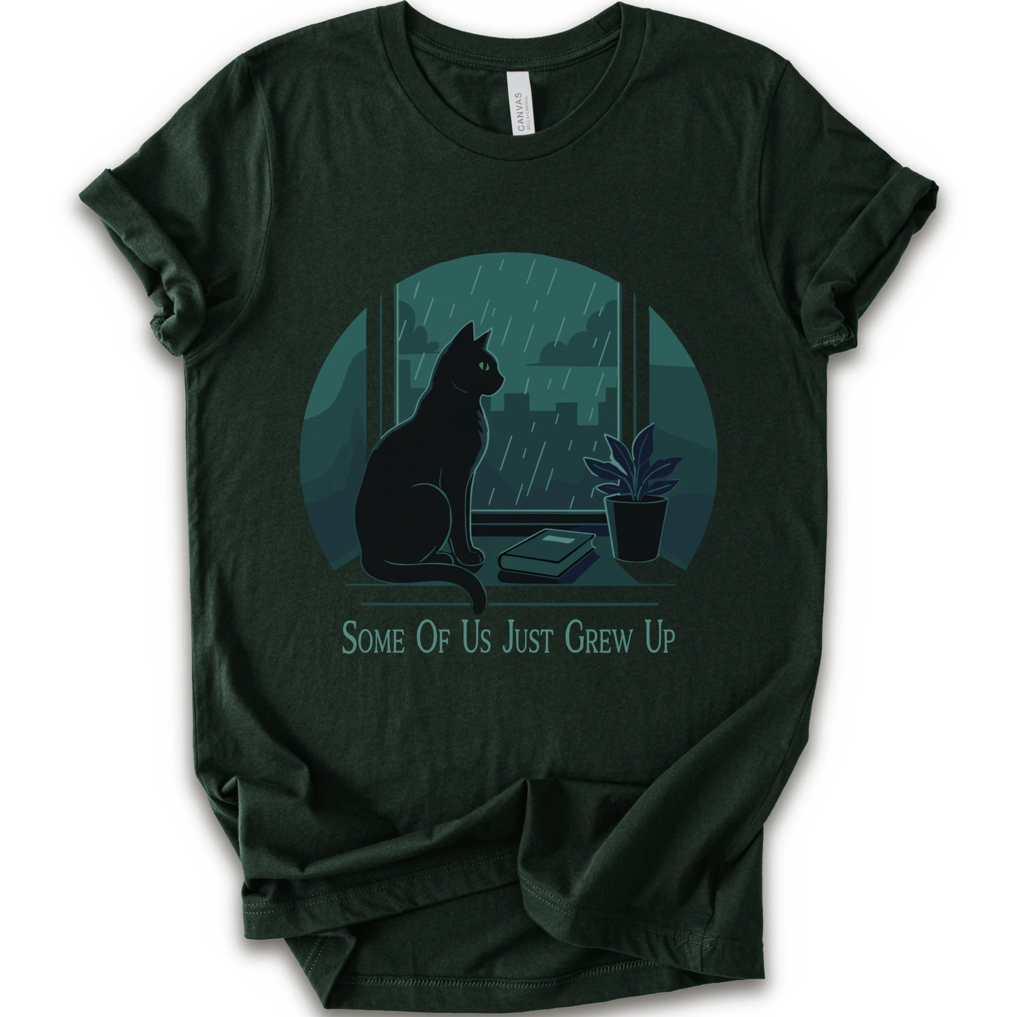 A forest short-sleeve crewneck t-shirt with a graphic print of a black cat sitting by a window in the rain, next to a small potted plant, with the text 'SOME OF US JUST GREW UP' printed below.