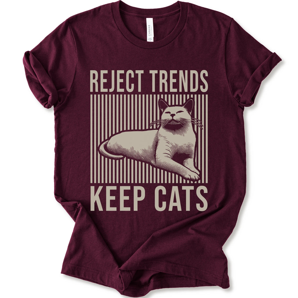 A maroon short-sleeve t-shirt with a vintage-style graphic featuring a cat and the text 'REJECT TRENDS KEEP CATS' in beige.