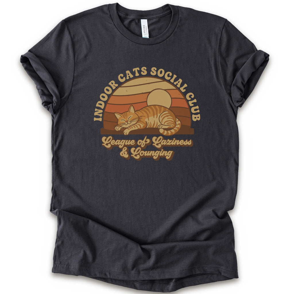 A dark grey short-sleeve crewneck t-shirt featuring a retro-style graphic of an orange tabby cat sleeping under a sunset, with the text 'INDOOR CATS SOCIAL CLUB' and 'League of Laziness & Lounging'.